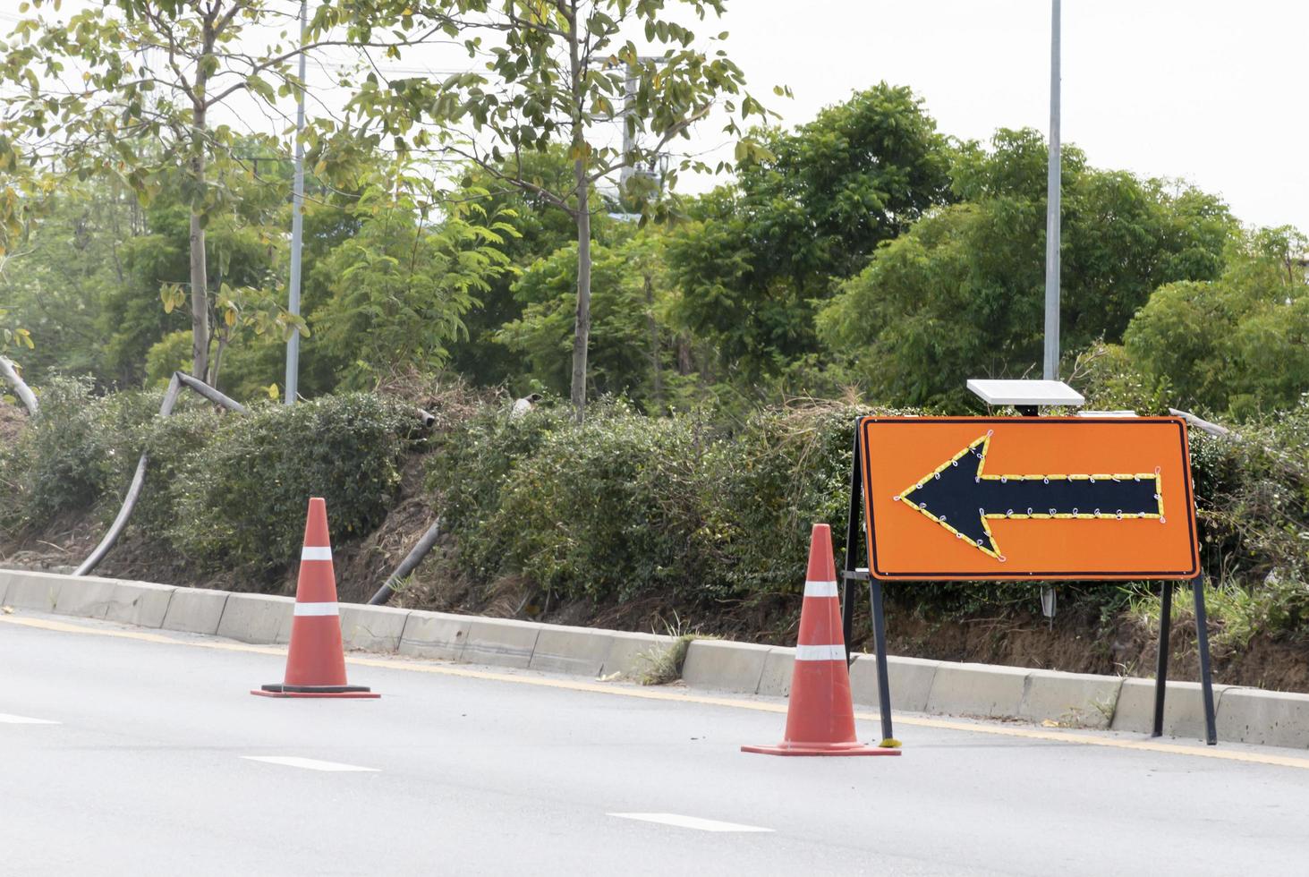 oranje verkeer teken met pijl icoon en signaal kegels Aan snelweg foto