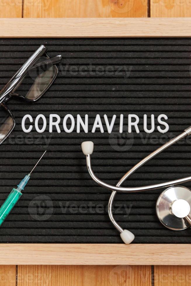 tekstuitdrukking coronavirus spuit en stethoscoop op zwarte letterbordachtergrond. nieuw coronavirus 2019-ncov, mers-cov midden-oosten respiratoir syndroom coronavirus afkomstig uit Wuhan China foto