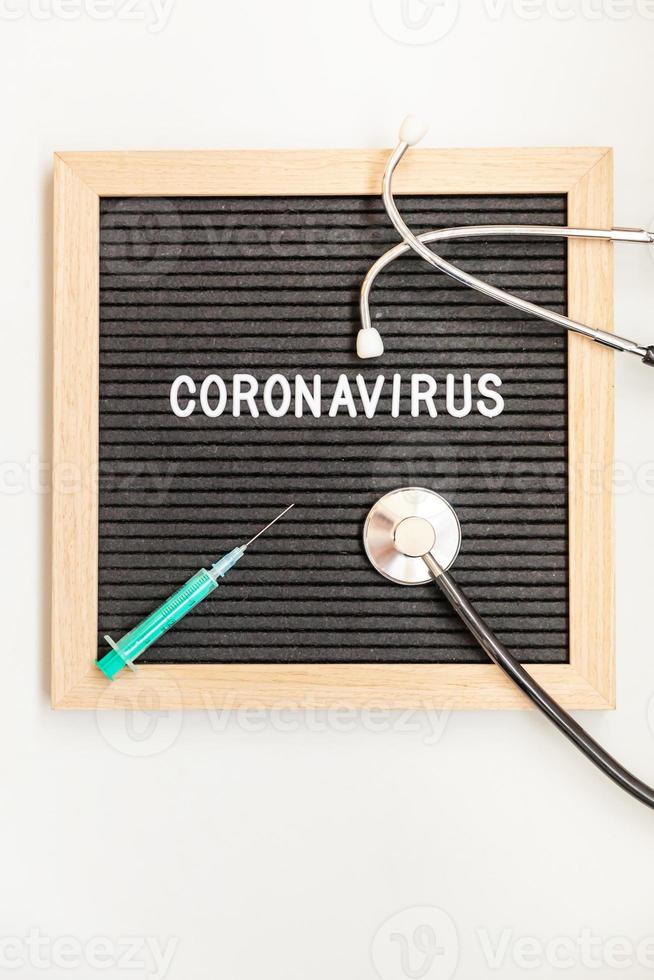 tekstuitdrukking coronavirus spuit en stethoscoop op zwarte letterbordachtergrond. nieuw coronavirus 2019-ncov, mers-cov midden-oosten respiratoir syndroom coronavirus afkomstig uit Wuhan China foto