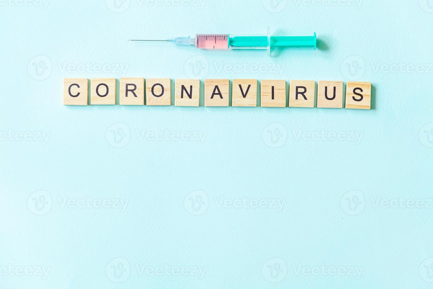 tekstuitdrukking coronavirus en spuit op blauwe pastelachtergrond. nieuw coronavirus 2019-ncov mers-cov covid-19 midden-oosten respiratoir syndroom coronavirus virus vaccin concept. foto