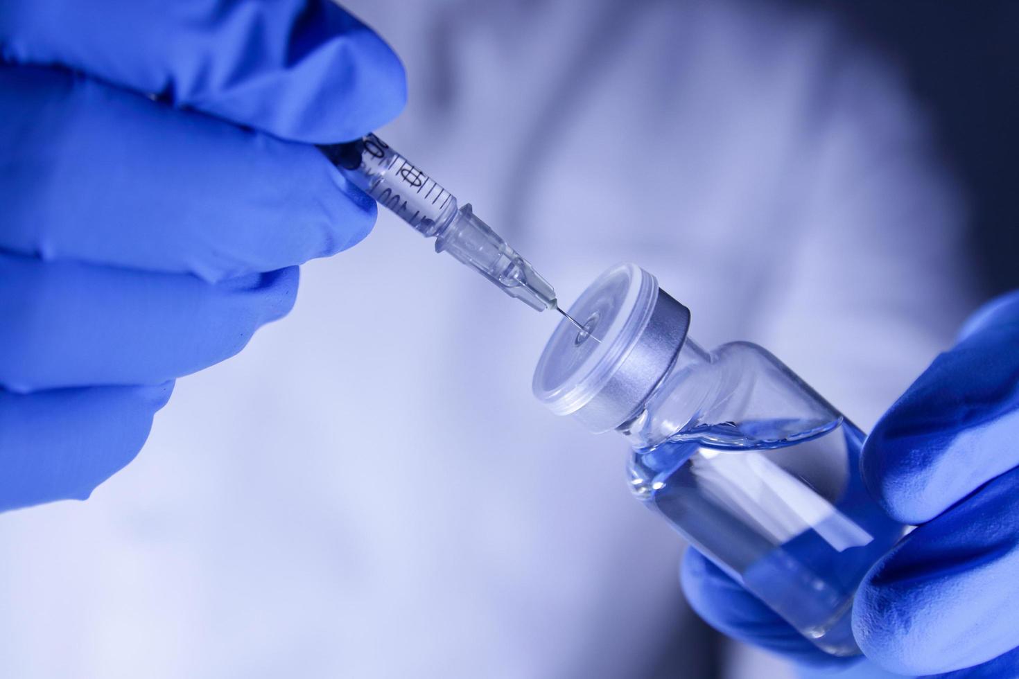artsen of wetenschappers houden injectiespuiten en flesjes met de covid-19 vaccin naar proberen injecties naar traktatie patiënten in ziekenhuizen. medisch experimenten voorkomen de verspreiding van de coronavirus foto