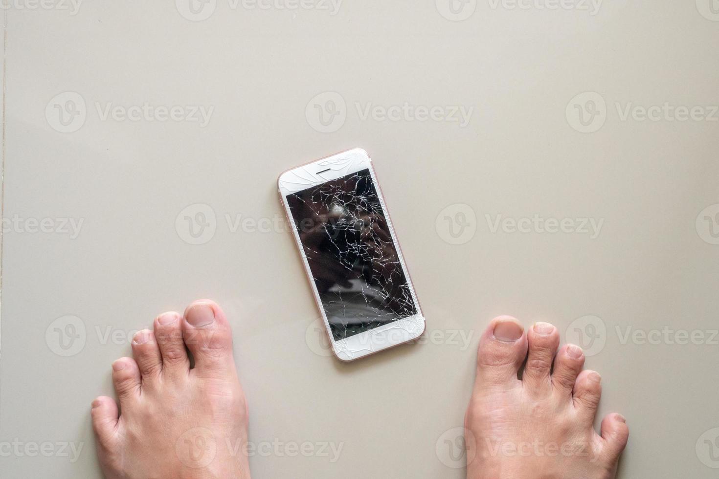 Mens op zoek Bij mobiel telefoon met gebroken glas scherm Aan de verdieping foto