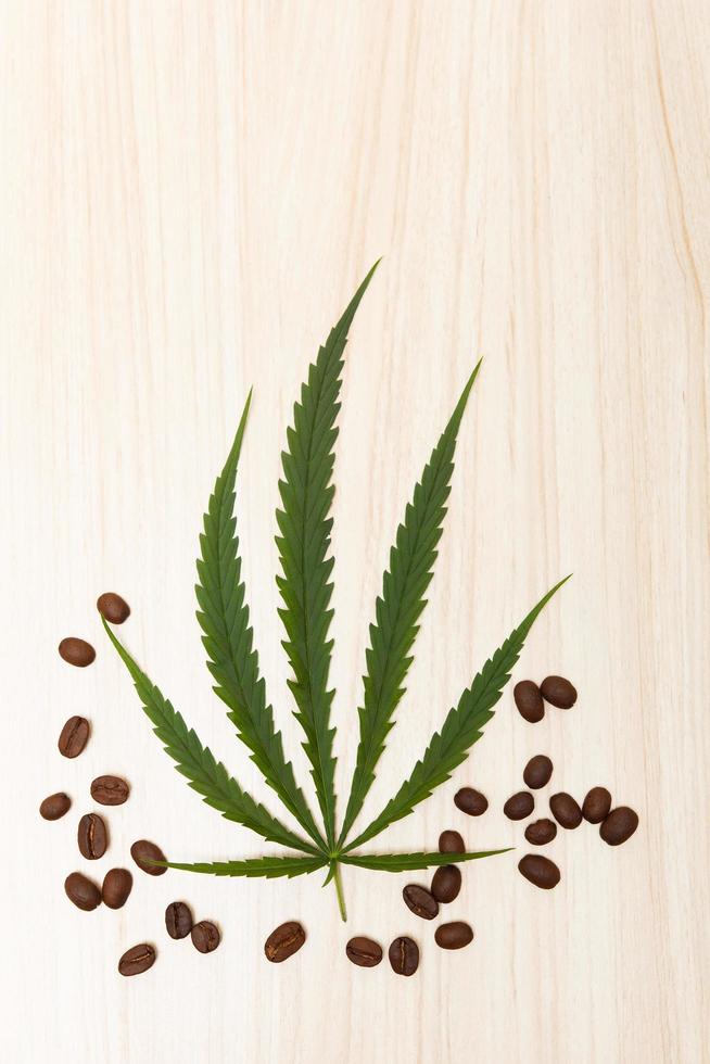 koffiebonen in een houten lepel met cannabisbladeren op een houten table.copy space.flat lay.top-down.top view. foto