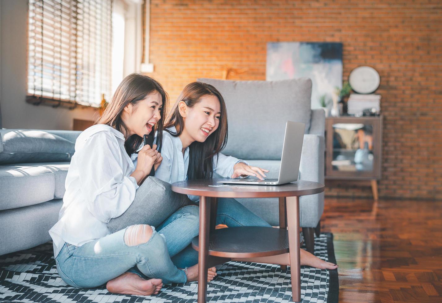 twee Aziatische vrouwen lachen tijdens het werken met laptop thuis foto