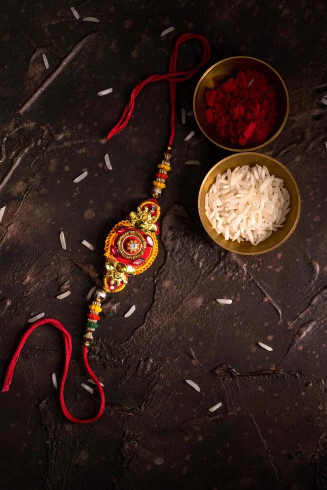 rakhi, rijstkorrels en kumkum op gestructureerde donkere achtergrond foto