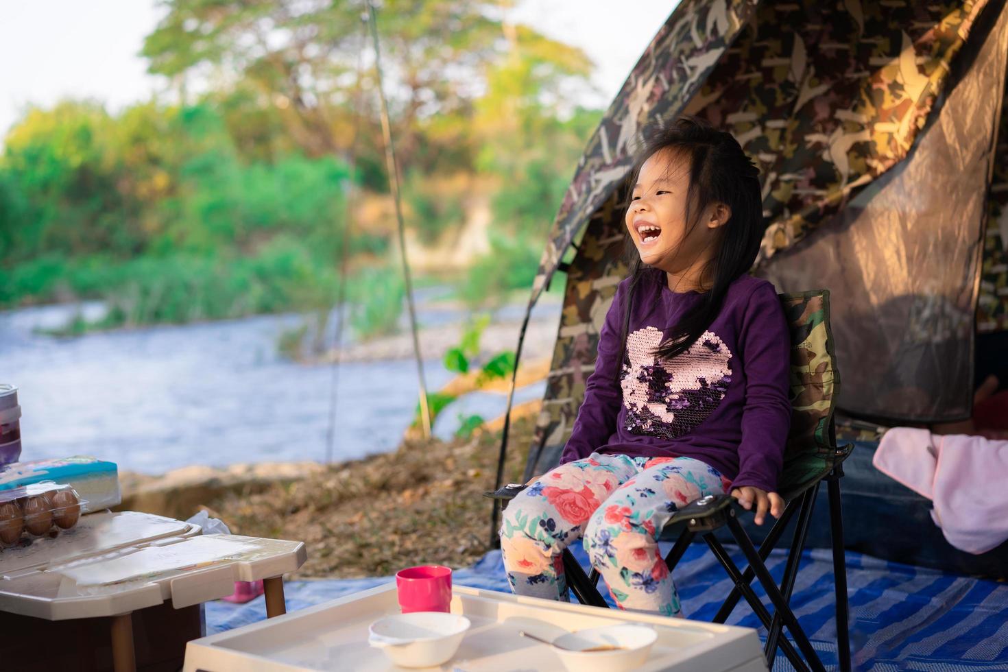 jong meisje, zittend op een camping, glimlachend foto