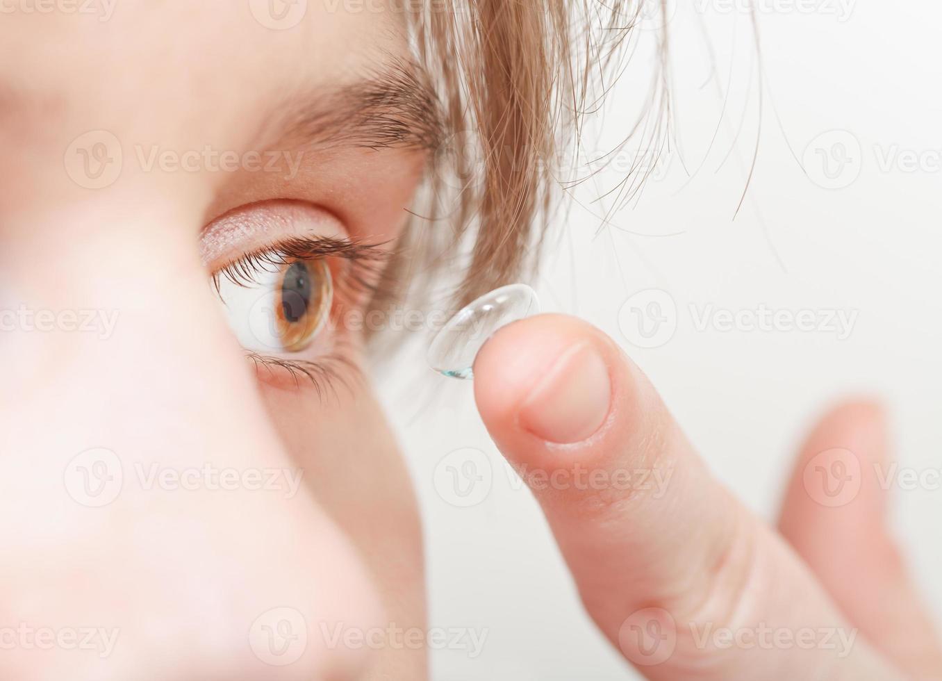 jonge vrouw voegt corrigerende lens in het oog in foto
