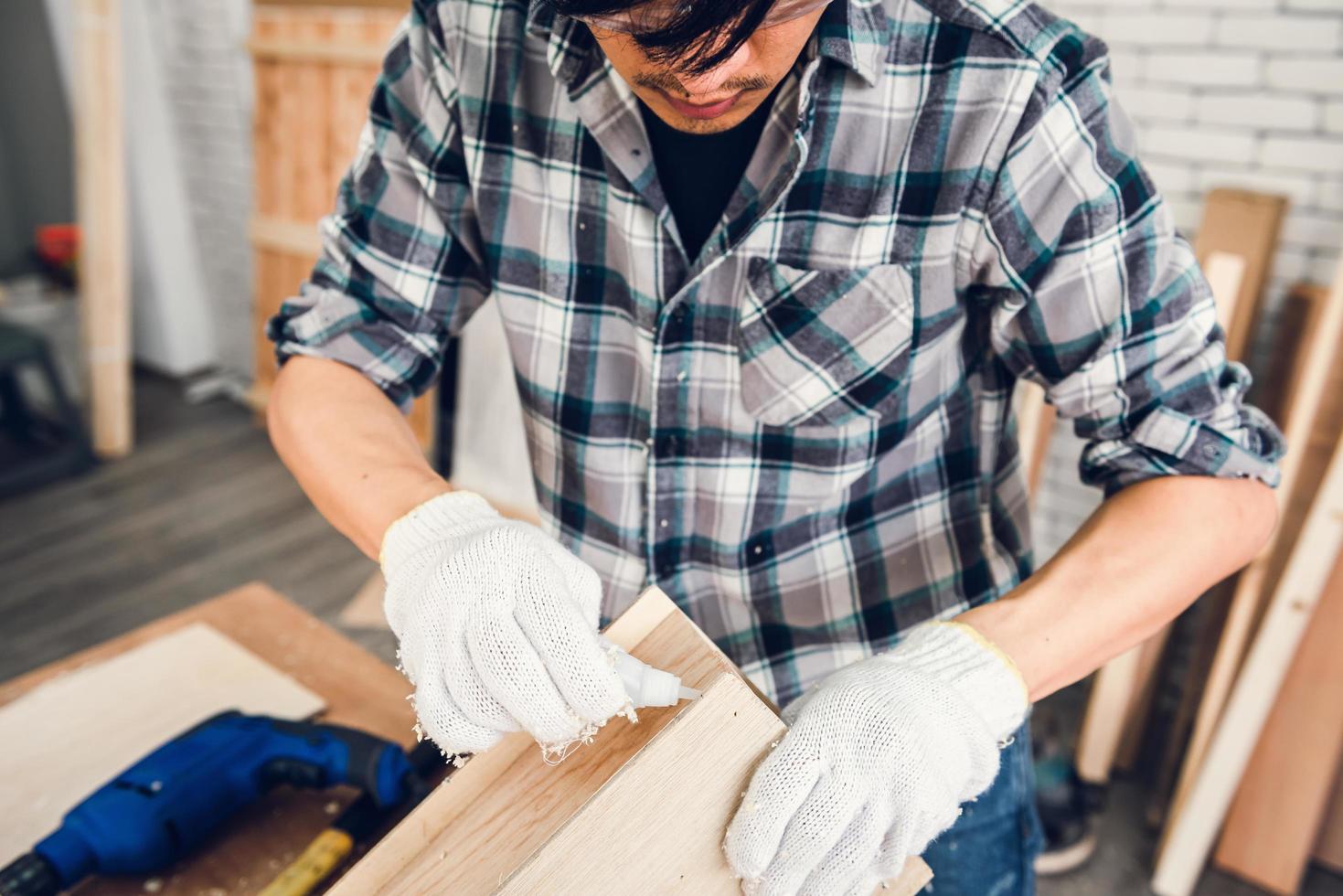 ambachtsman is hout aan elkaar lijmen in werkplaats foto