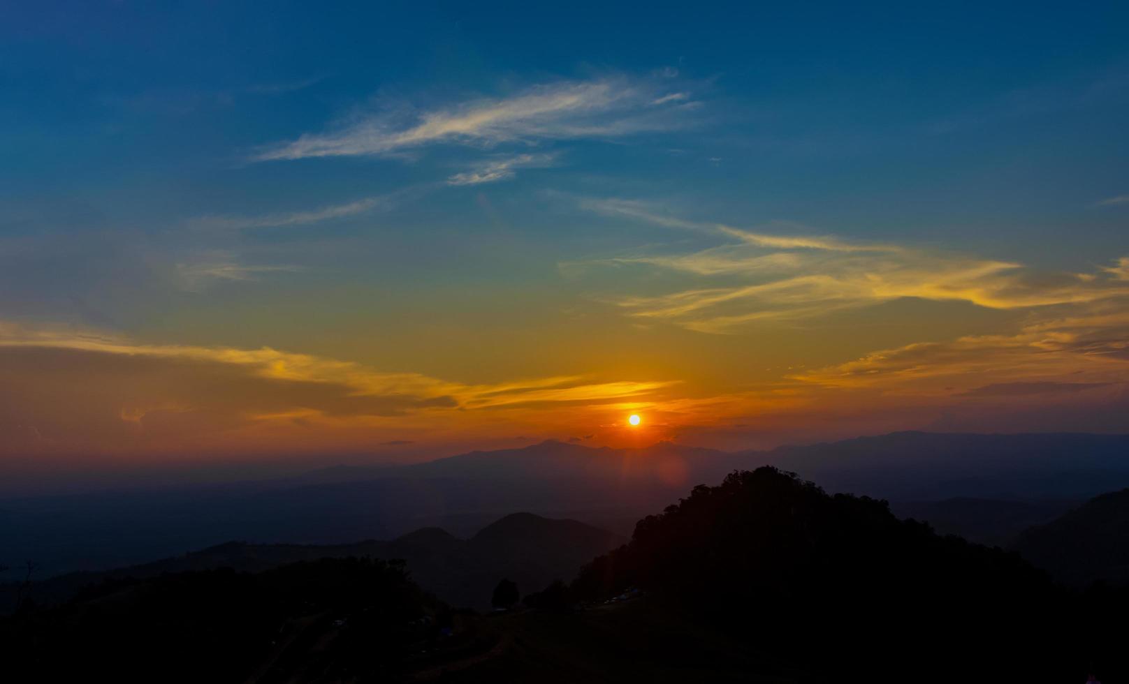 ondergaande zon over bergtoppen foto