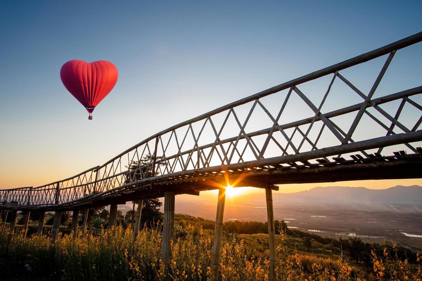 hartvormige hete luchtballon die over zonsondergang vliegt foto