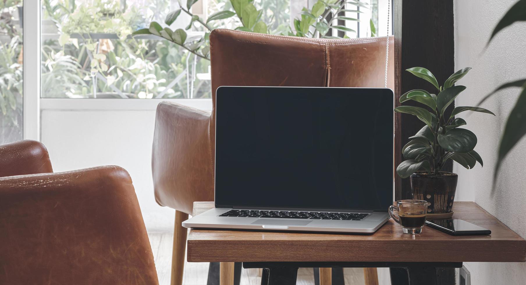 laptop met espresso en telefoon in de woonkamer foto