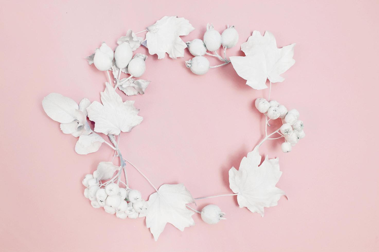 cirkel van witte bessen en witte bladeren op roze achtergrond foto