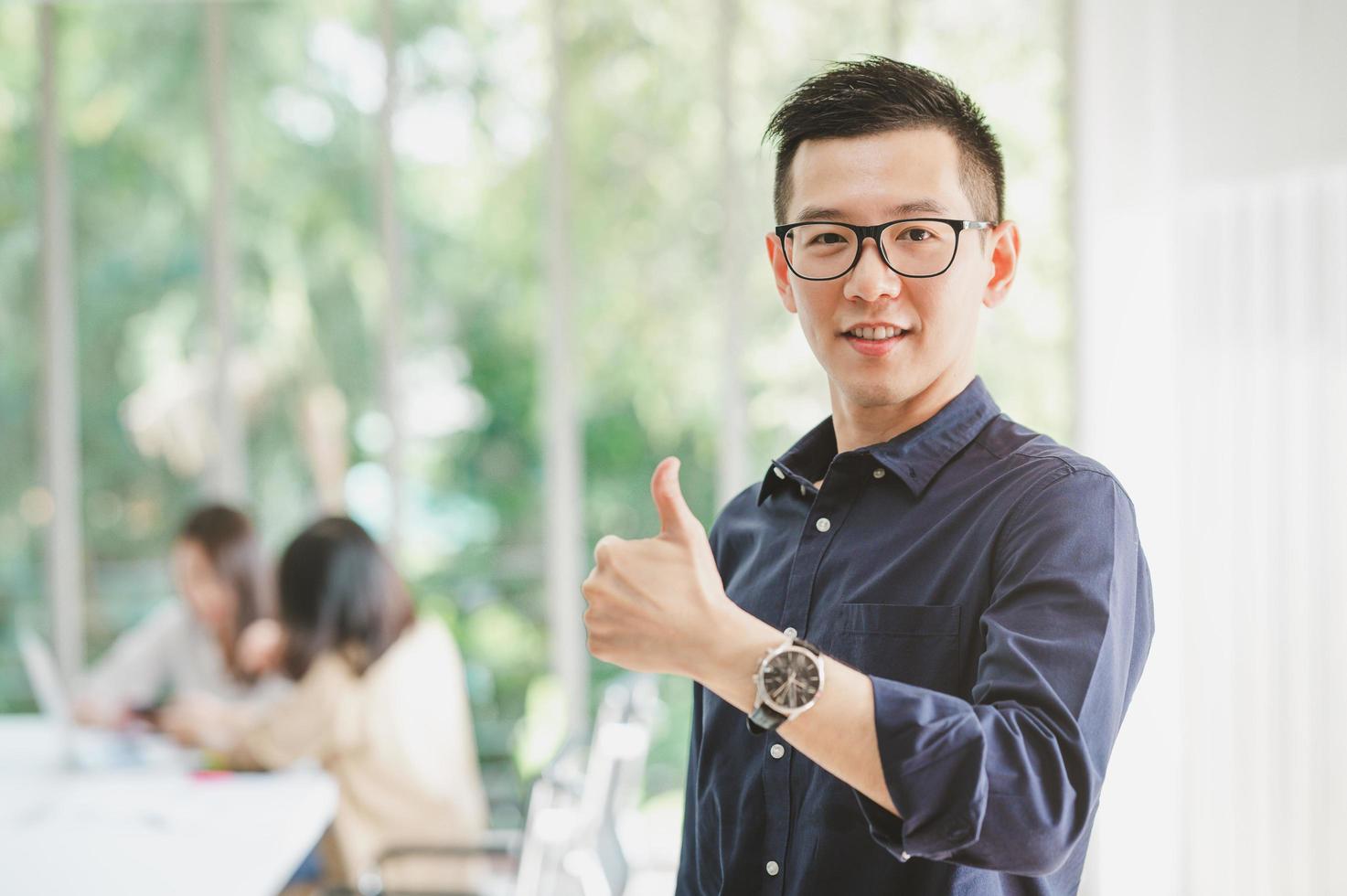 Aziatische zakenman lachend met thumbs up gebaar foto