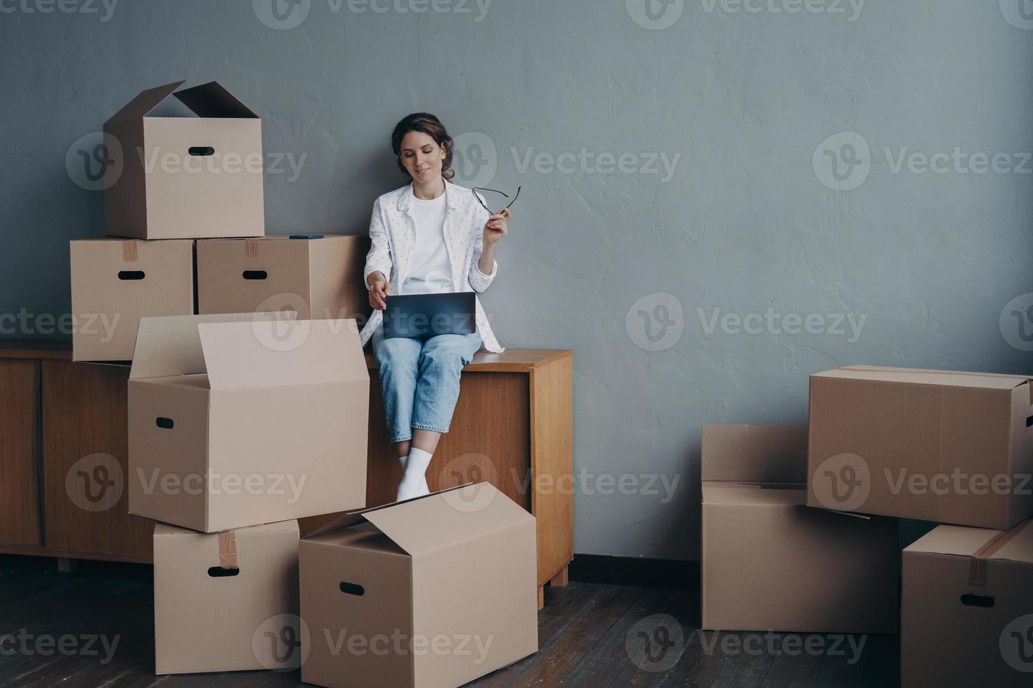 vrouw met karton dozen zoeken in beweging bedrijf Bij laptop voor verhuizing. vervoer onderhoud foto