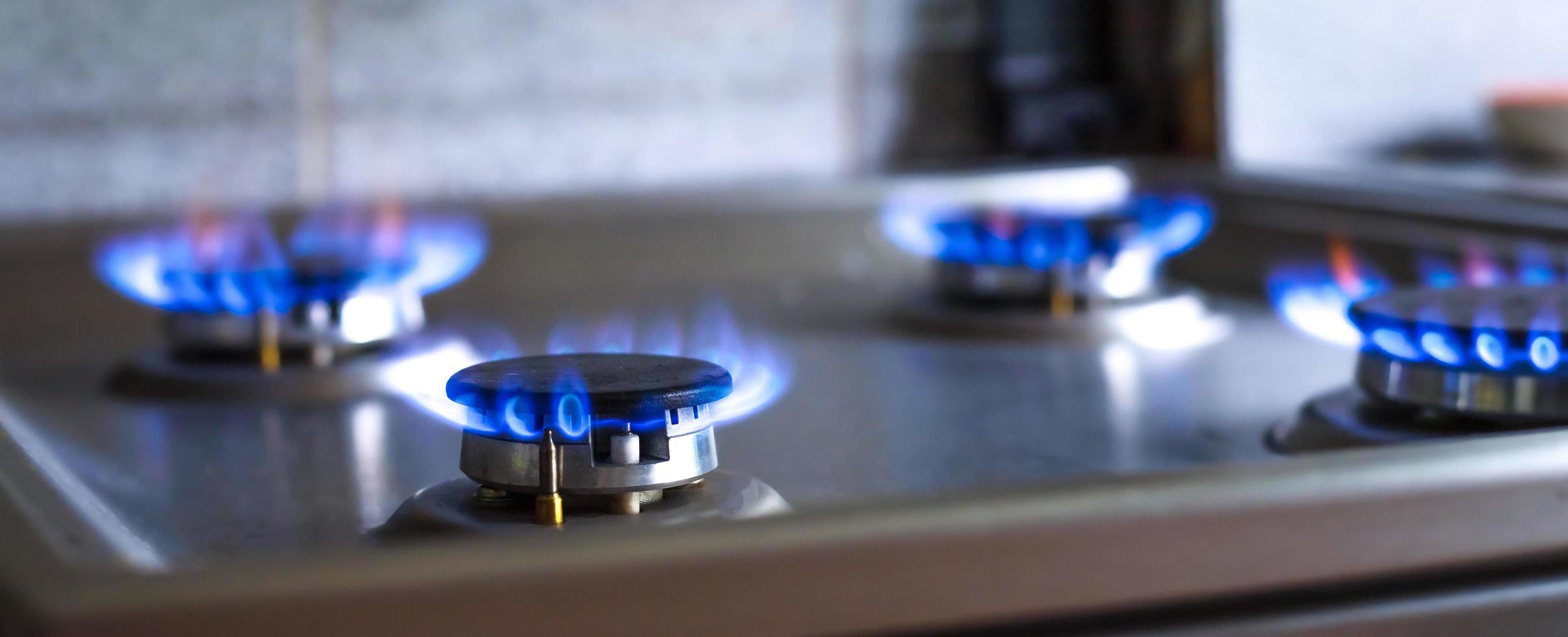 detailopname van een blauw brand van een keuken fornuis. 4 gas- branders met een brandend vlam. economie concept. breed banier foto