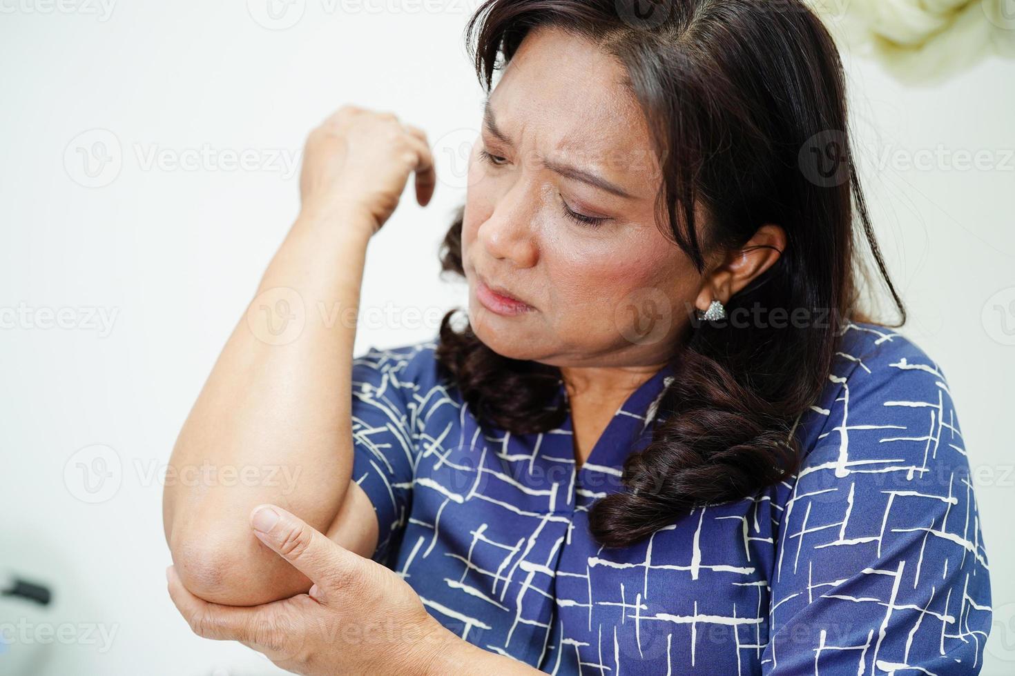 aziatische senior vrouw die elastische steun elleboogbrace draagt om pijn te verminderen. foto