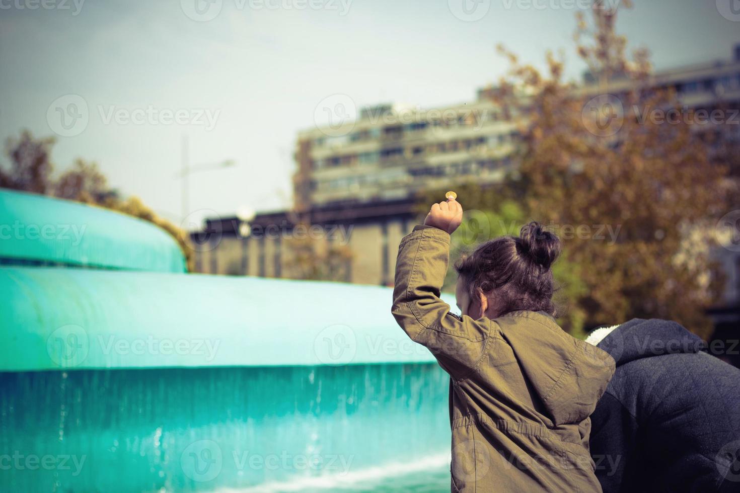 achterzijde visie van kinderen het werpen munten in fontein. foto