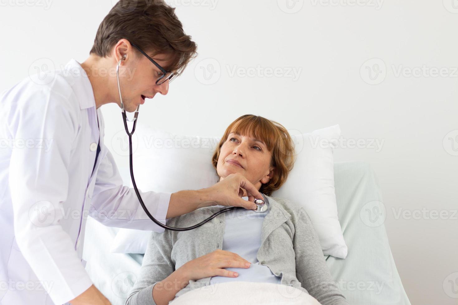 de dokter is onderzoeken de geduldig in de ziekenhuis. wit mannetje dokter onderzoeken een ouderen vrouw wit geduldig. foto