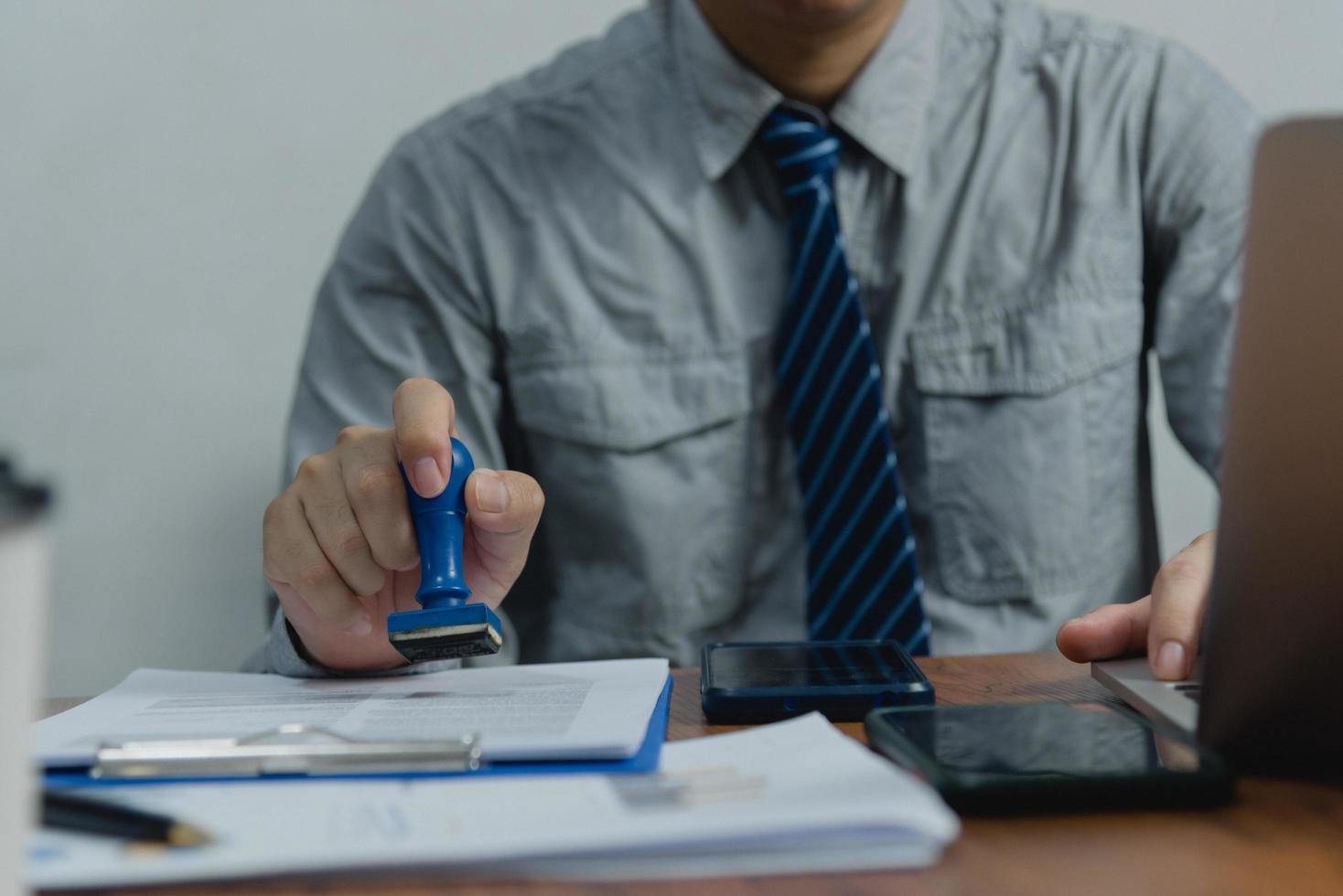 Mens stempelen goedkeuring van werk financiën bank of investering afzet documenten Aan bureau. foto