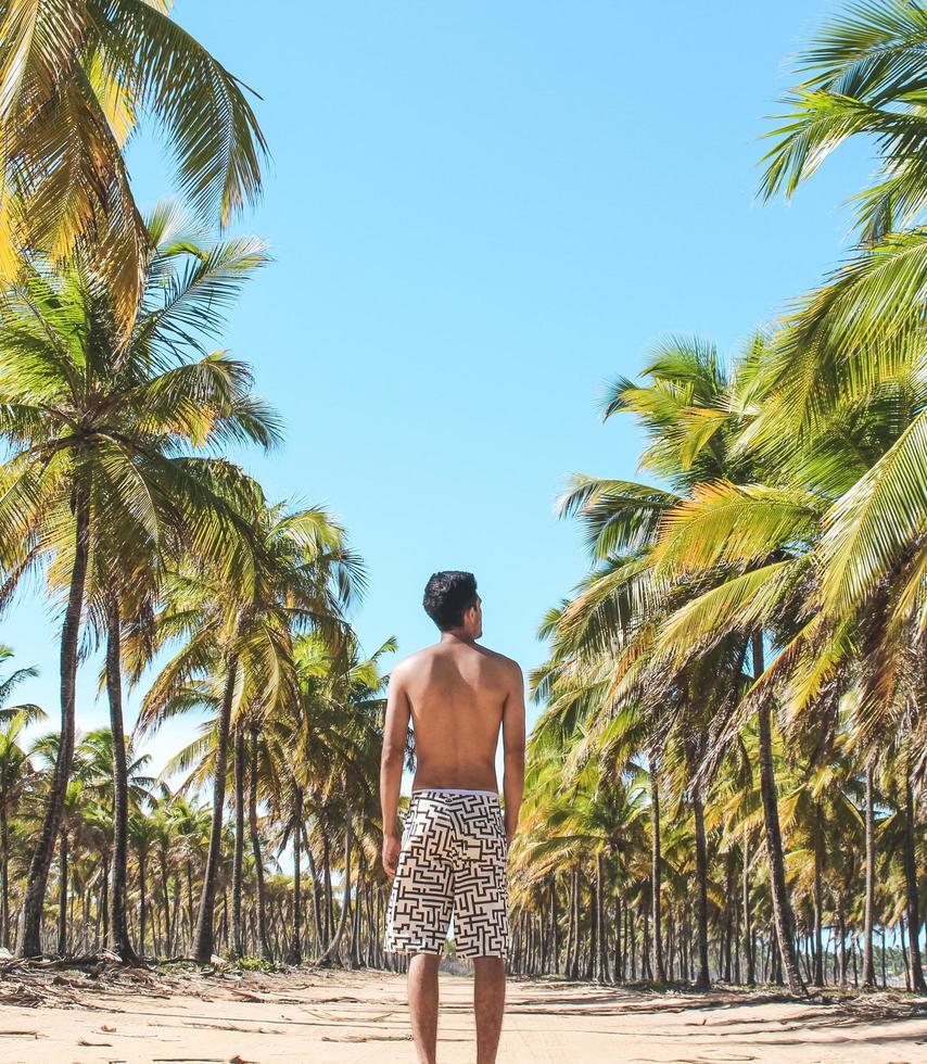 man die onder palmbomen op het strand foto