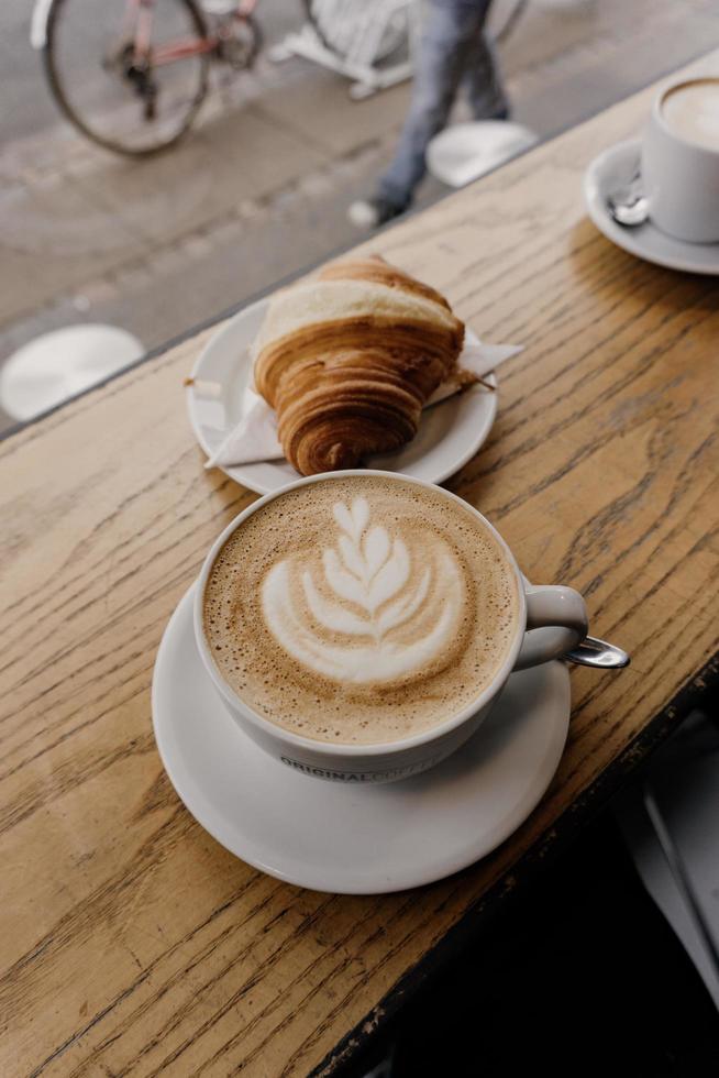 cappuccino en croissant op buitentafel foto