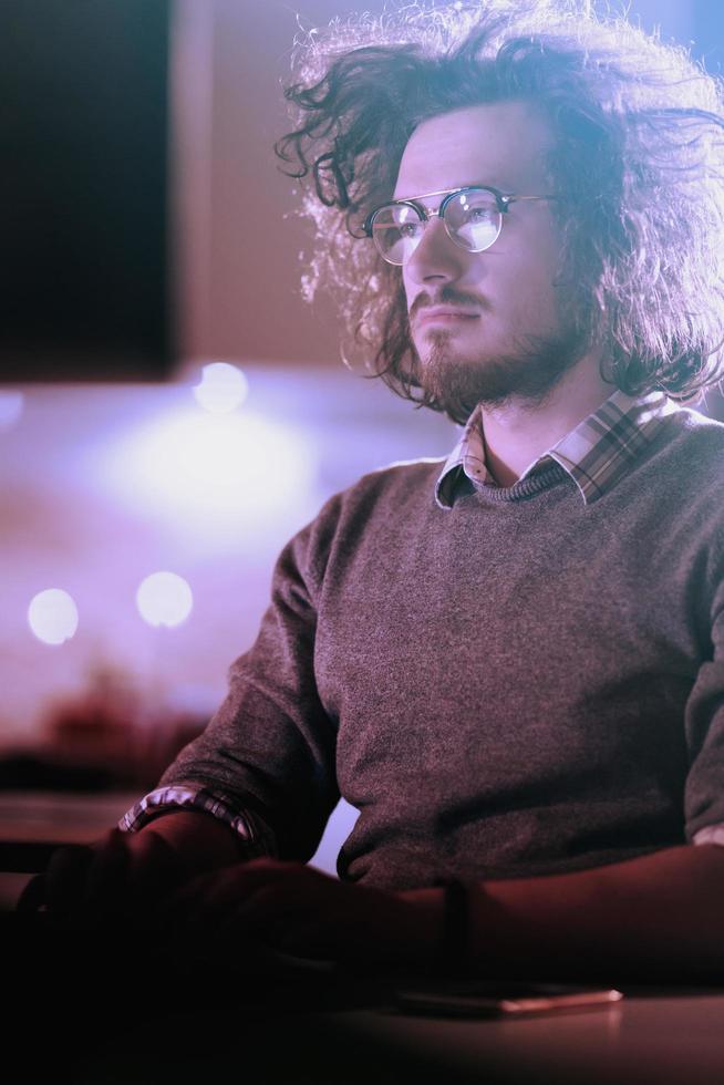 Mens werken Aan computer in donker kantoor foto