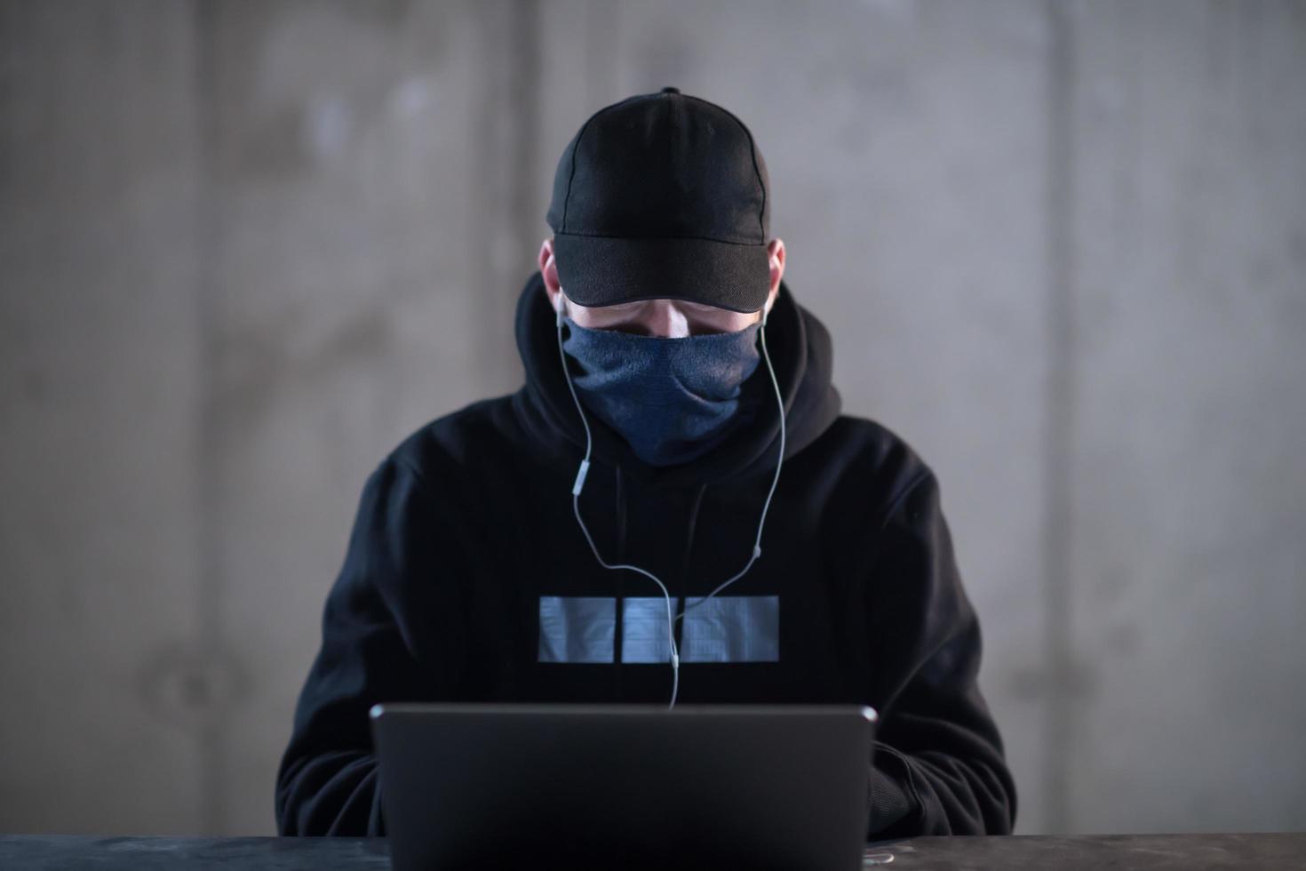 getalenteerd hacker gebruik makend van laptop computer terwijl werken in donker kantoor foto