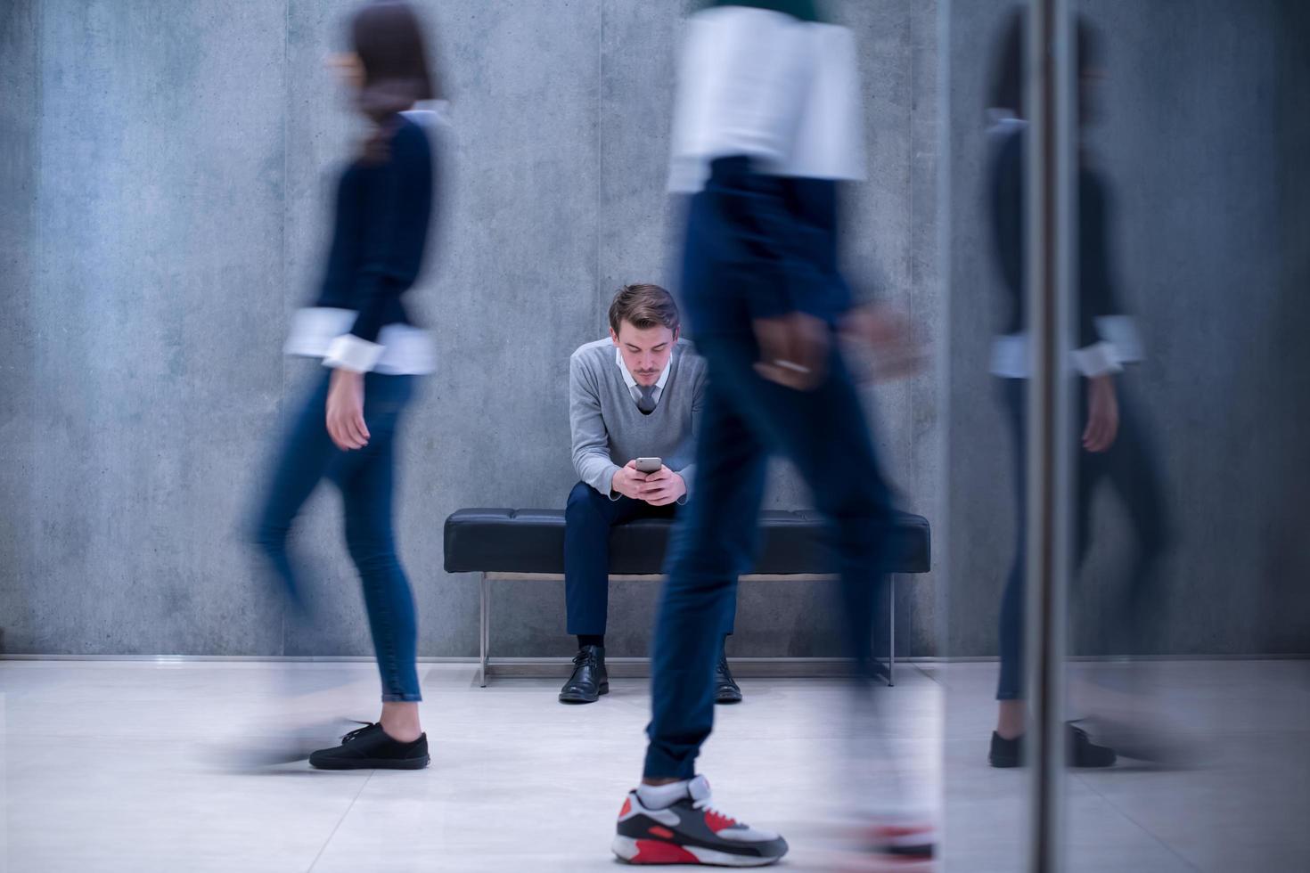 zakenman gebruik makend van mobiel telefoon terwijl zittend Aan de bank foto