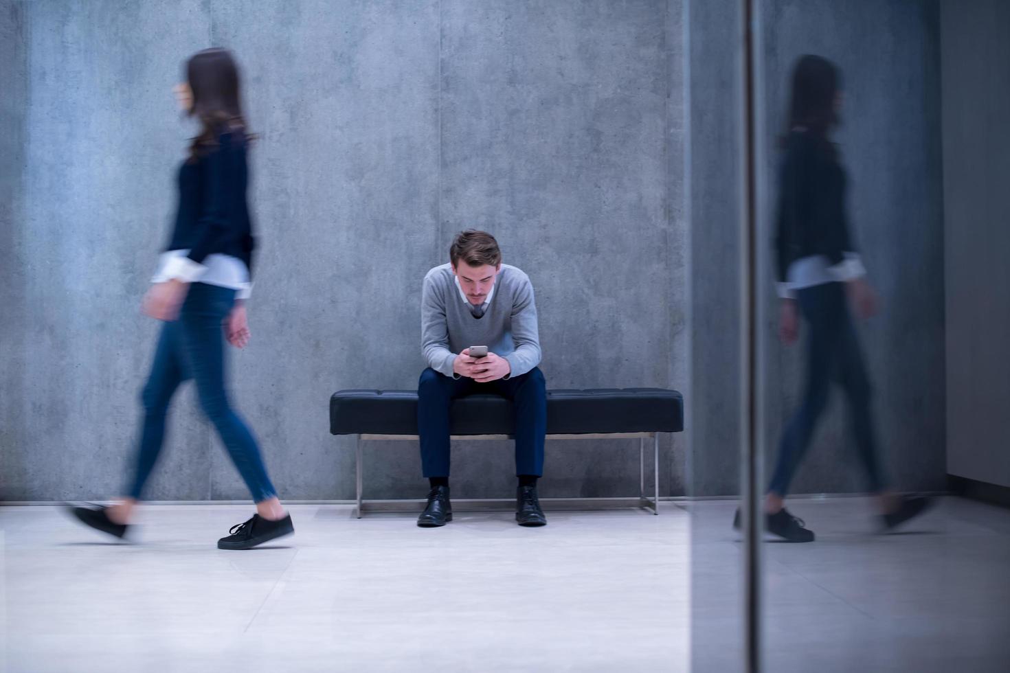 zakenman gebruik makend van mobiel telefoon terwijl zittend Aan de bank foto