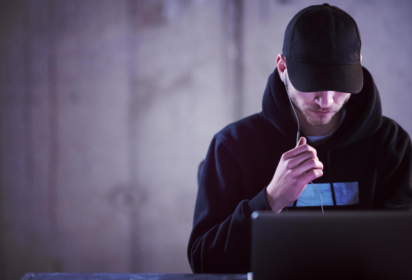 getalenteerd hacker gebruik makend van laptop computer terwijl werken in donker kantoor foto