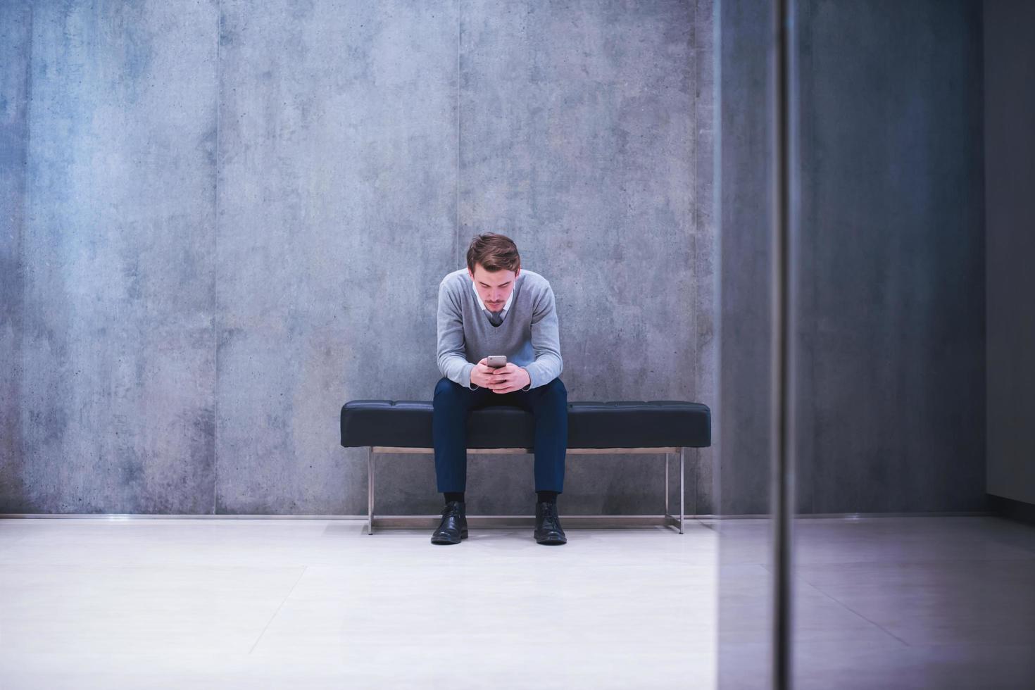 zakenman gebruik makend van slim telefoon terwijl zittend Aan de bank foto