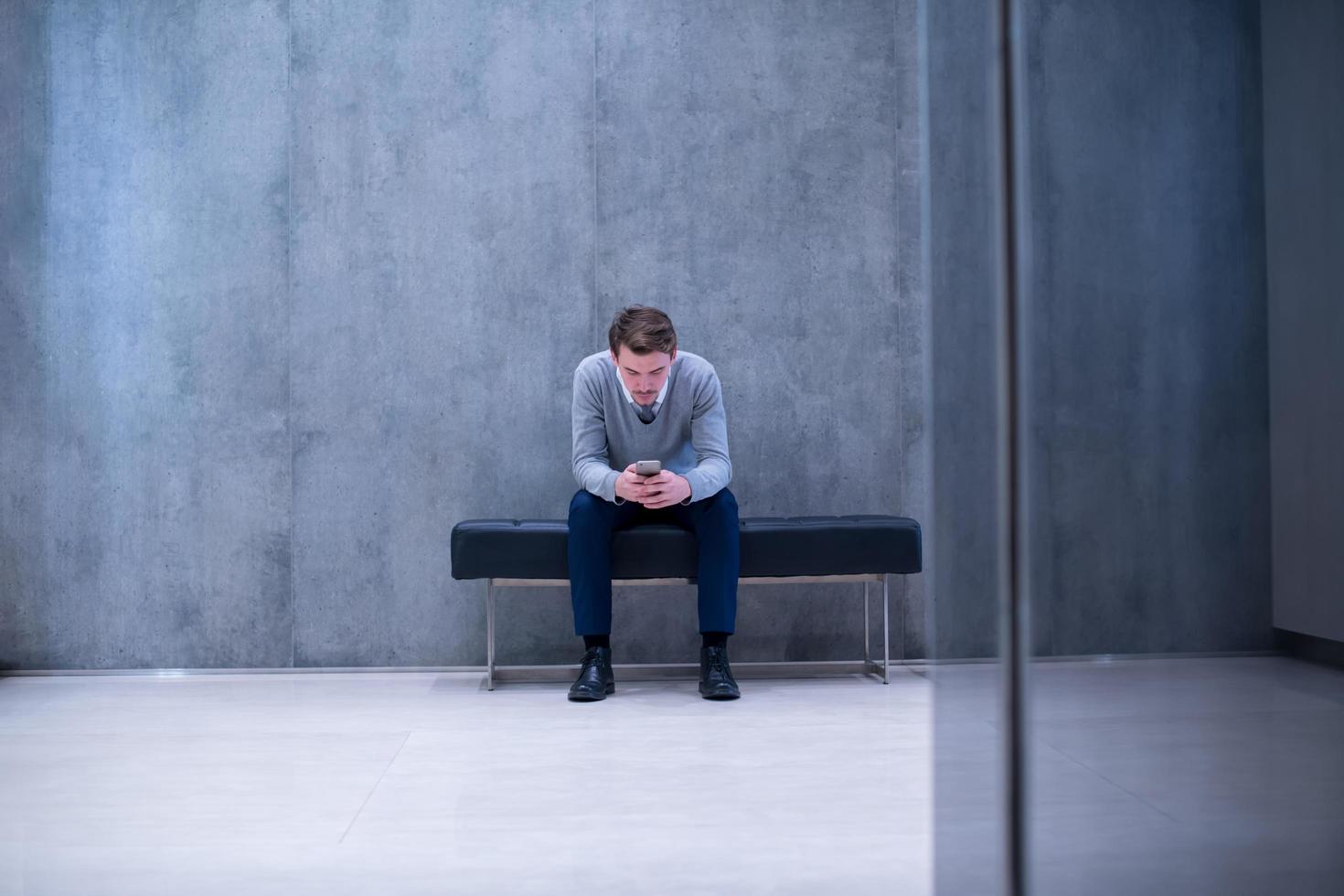 zakenman gebruik makend van slim telefoon terwijl zittend Aan de bank foto