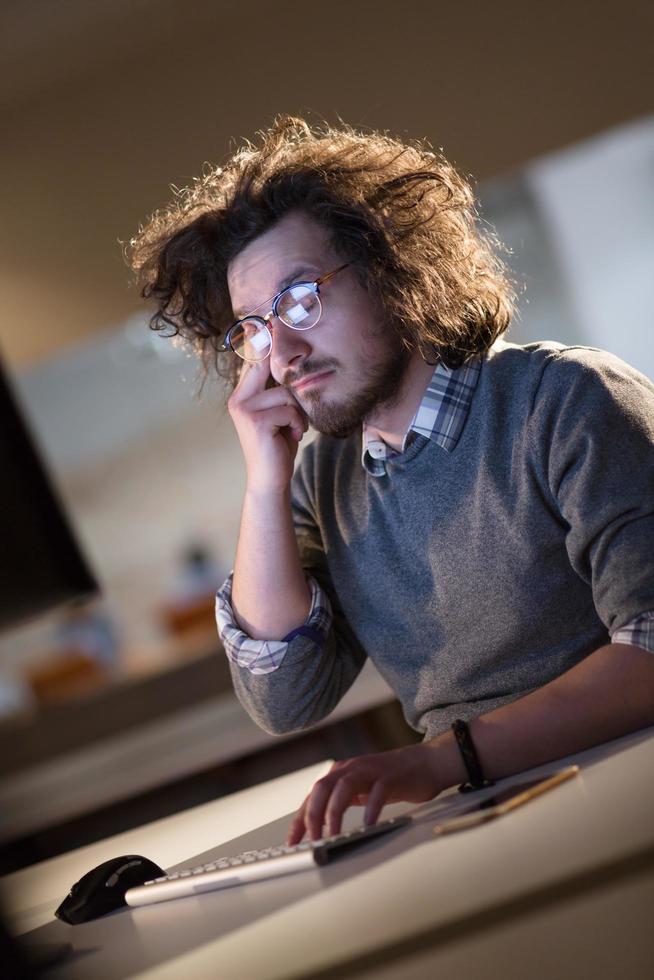 Mens werken Aan computer in donker kantoor foto