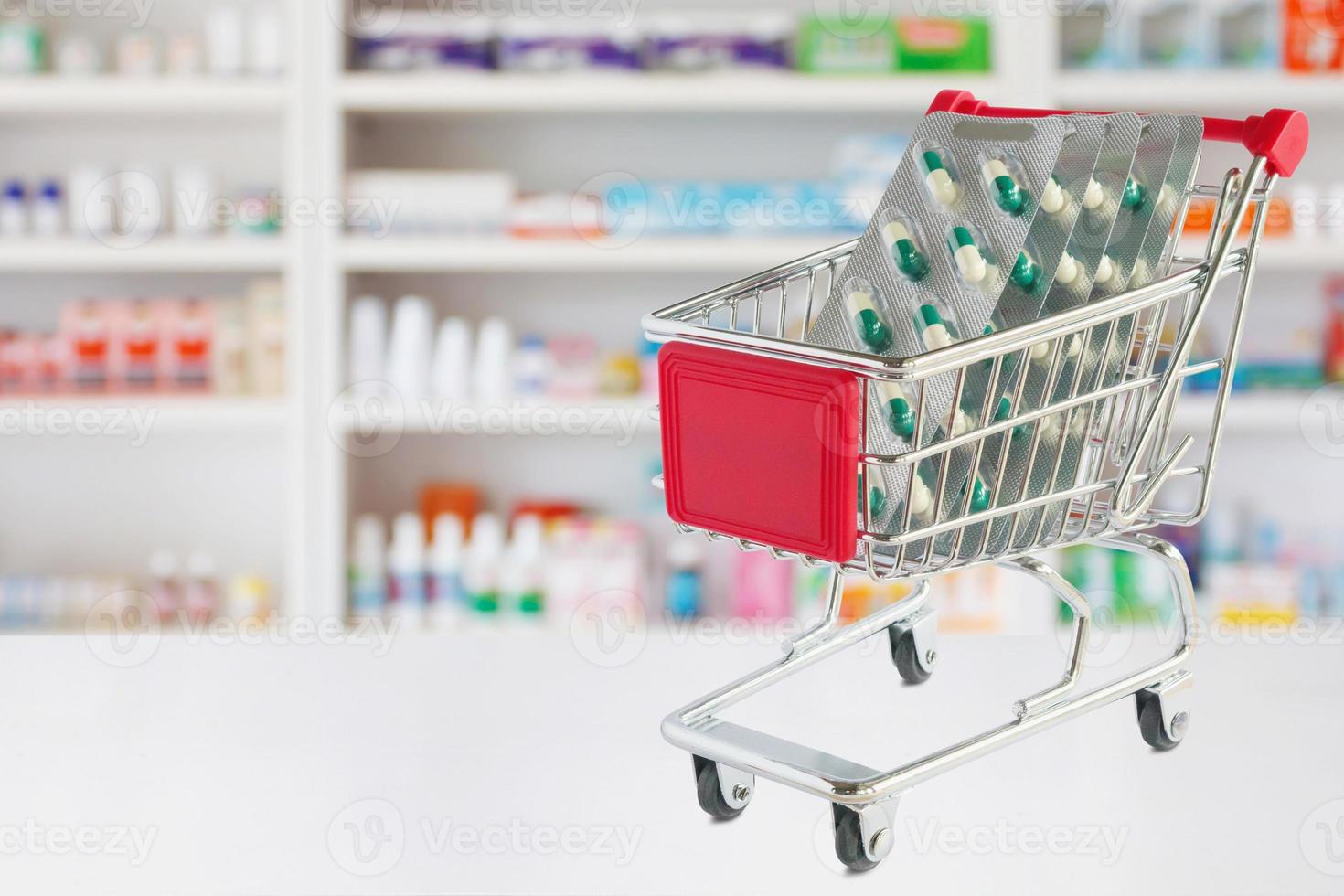 geneeskunde pillen capsule in winkelwagen op apotheek winkel teller met onscherpte drogisterij planken intreepupil achtergrond foto