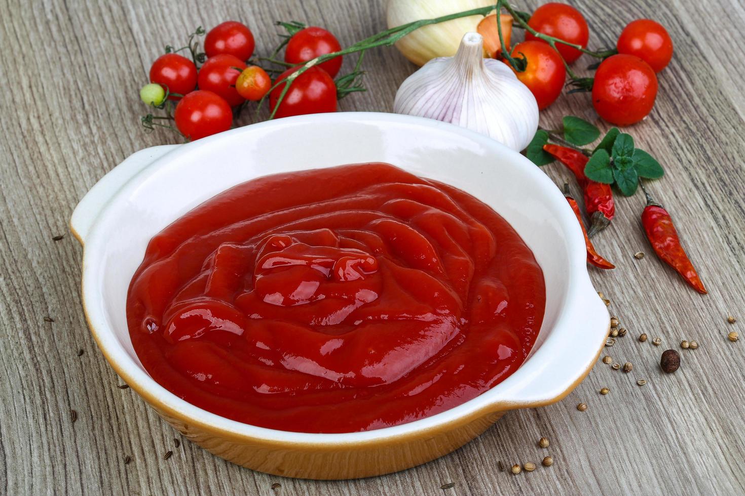 tomaat ketchup in een kom Aan houten achtergrond foto