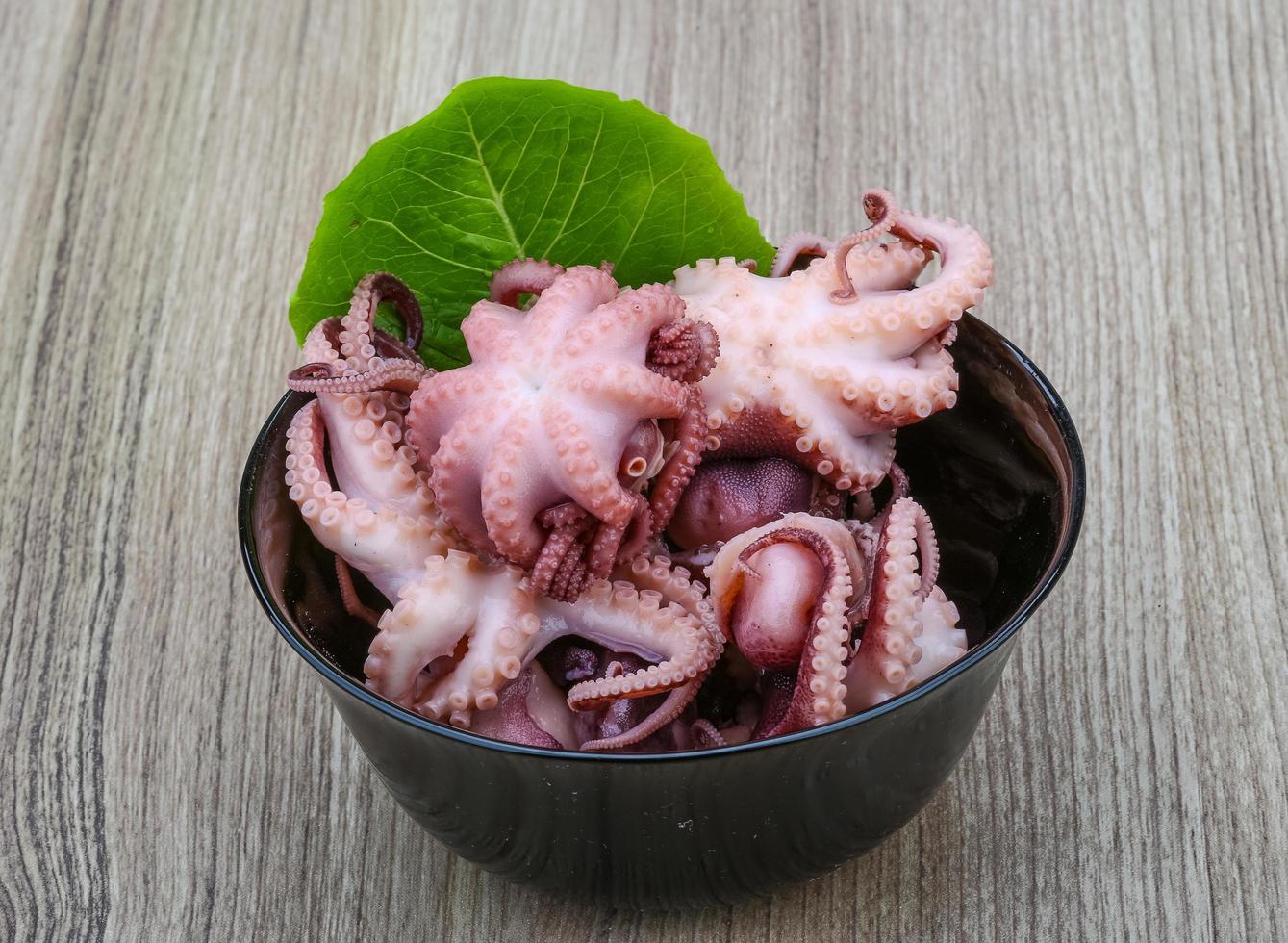 gemarineerde octopus in een kom op houten achtergrond foto