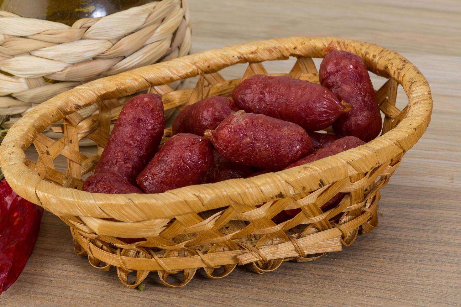 mini salami in een mand Aan houten achtergrond foto