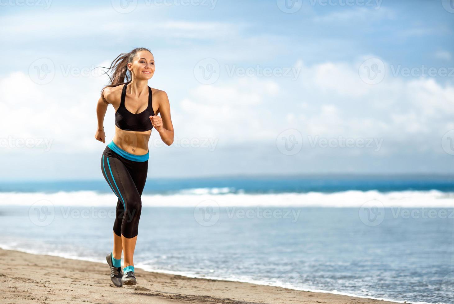 joggen atleet vrouw draait op zonnig strand foto
