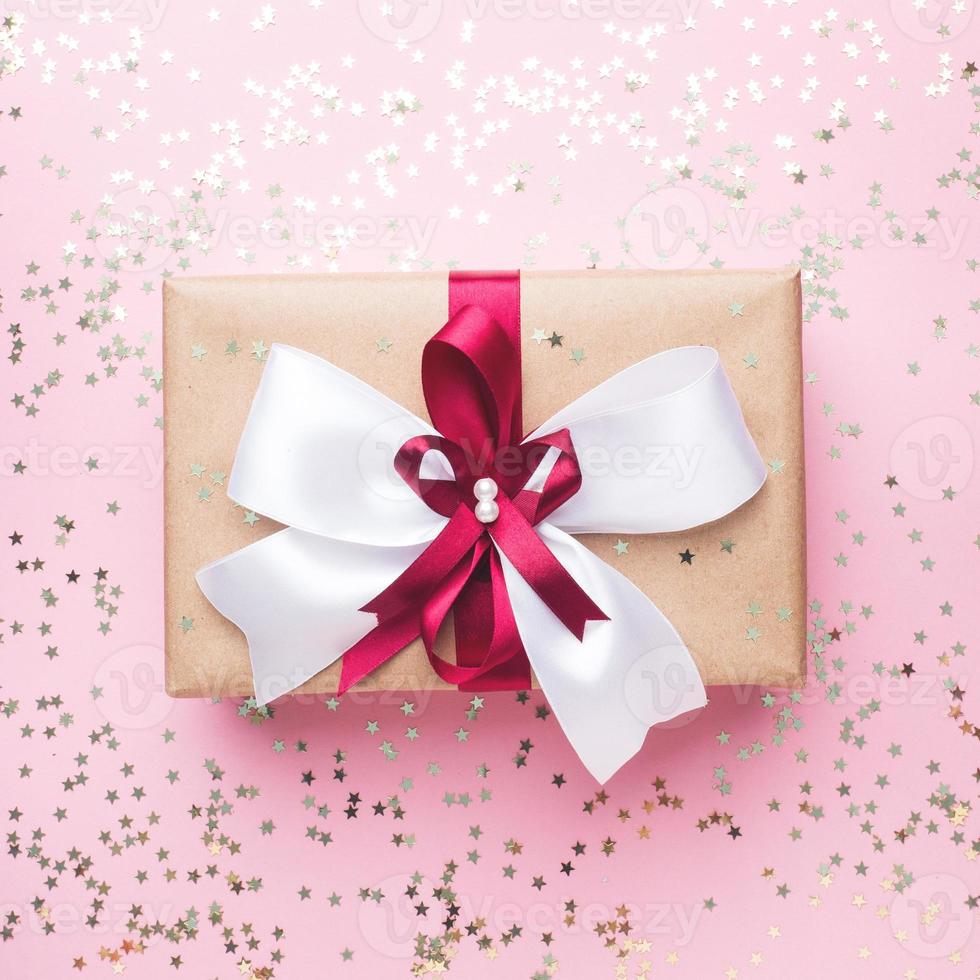 geschenk of Cadeau doos met een groot boog Aan een roze tafel top visie. flatlay samenstelling voor Kerstmis verjaardag, moeder dag of bruiloft. foto
