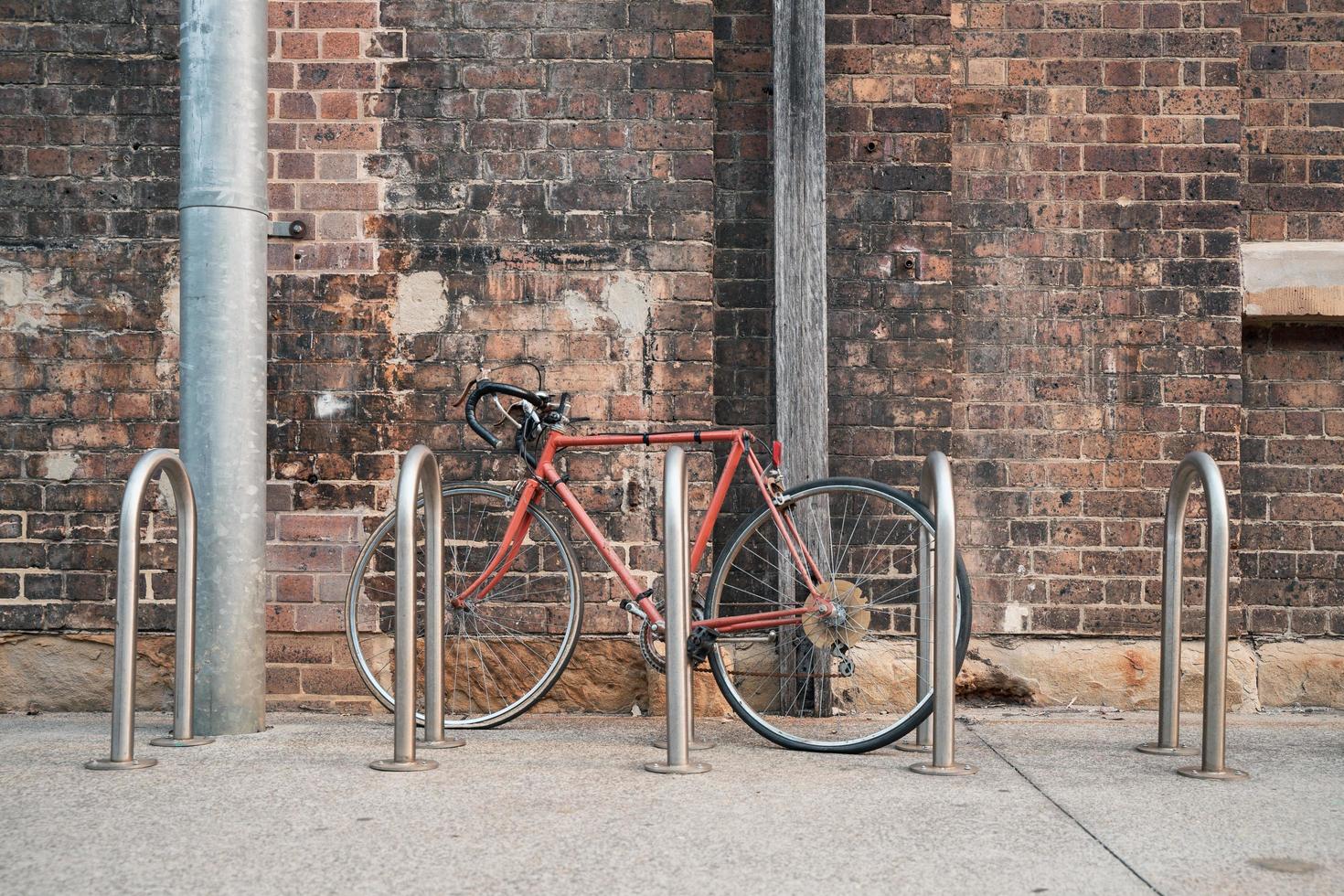 rode fiets naast fietsenrek dichtbij muur foto