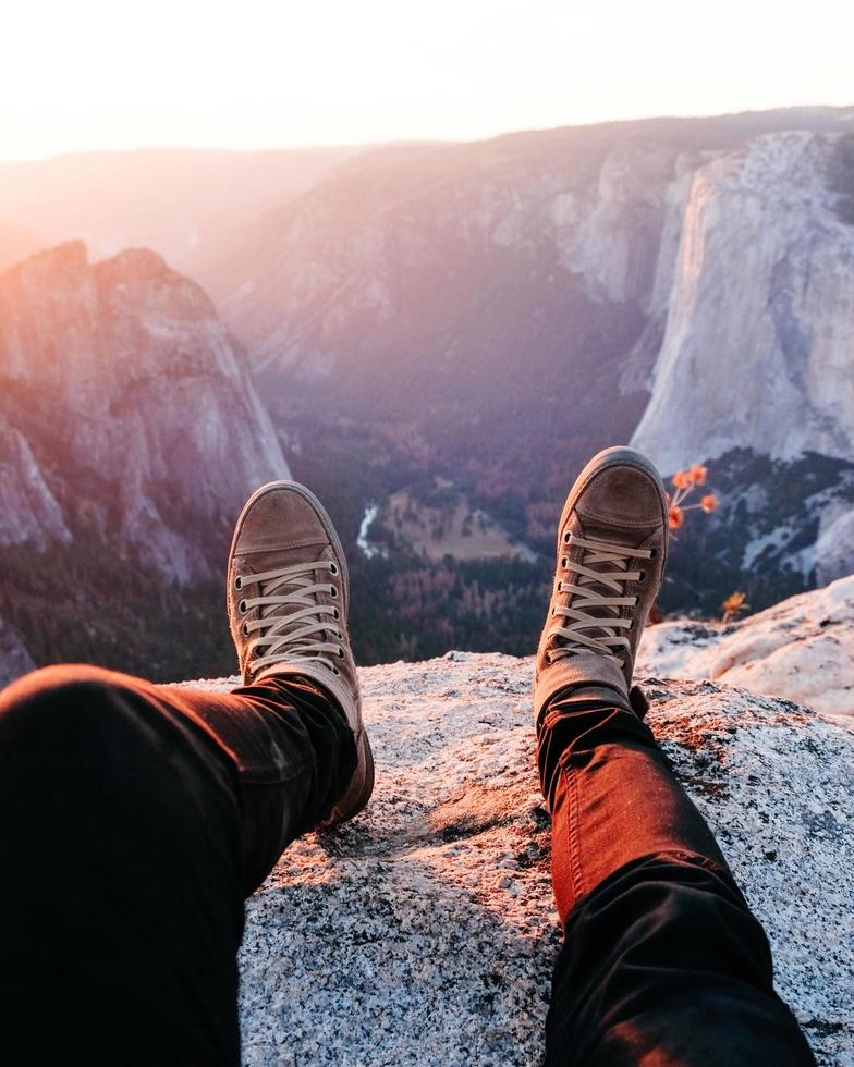 persoon zittend op rotsachtige berg tijdens zonsopgang foto
