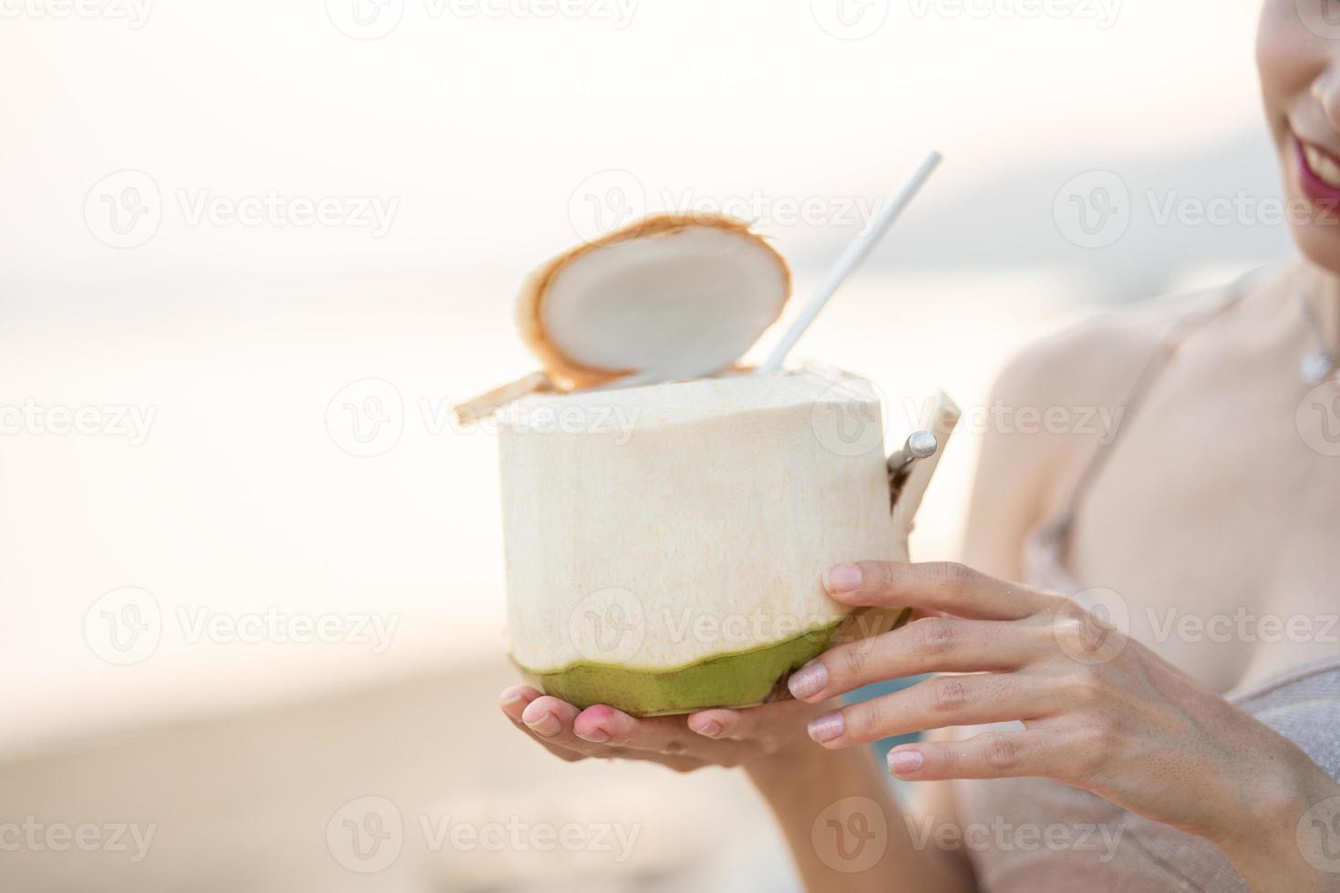 vrouw drinken vers kokosnoot Aan de strand, romantisch zonsondergang moment. zomer vakantie. foto