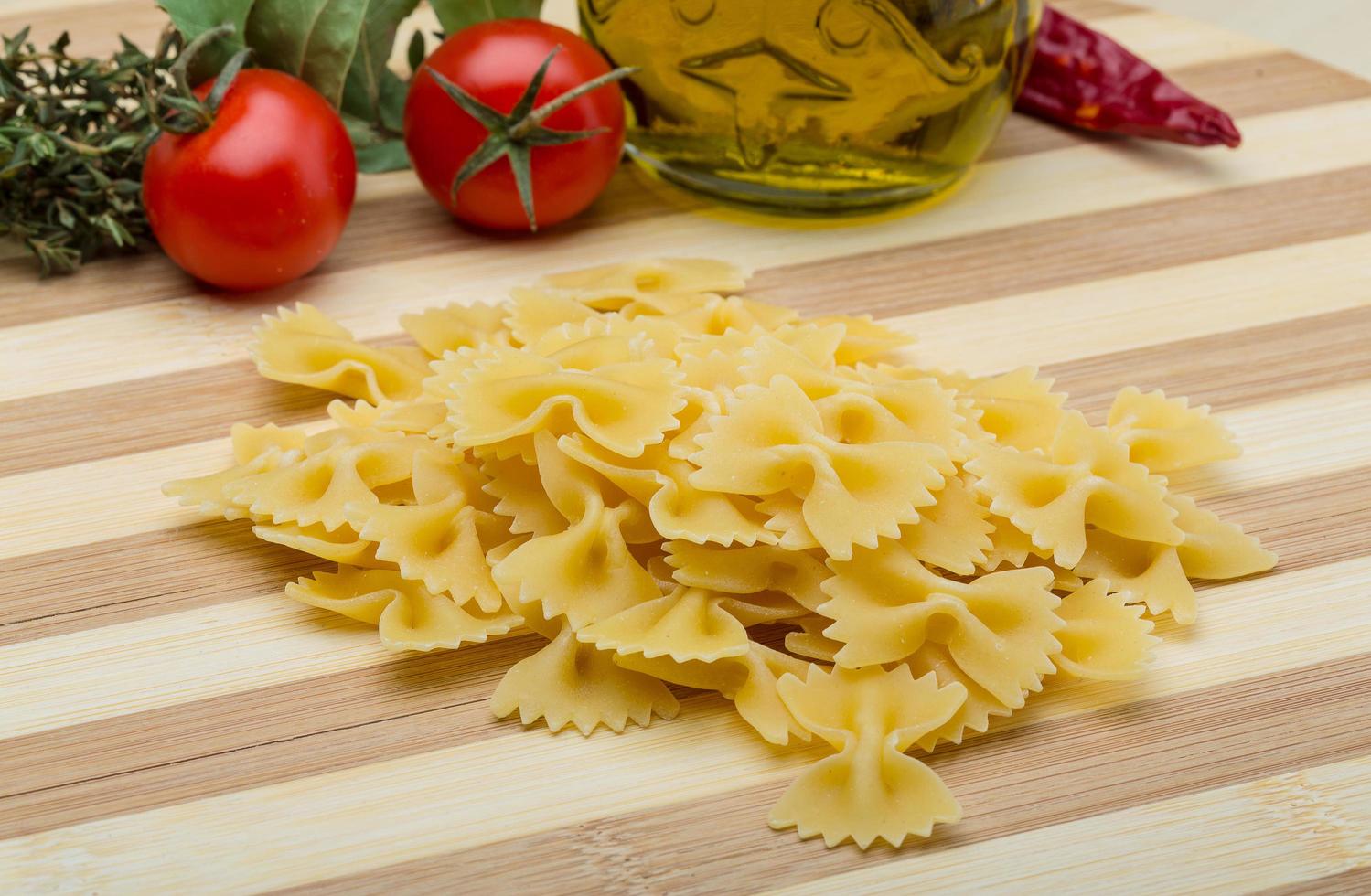 rauw farfalle Aan houten bord en houten achtergrond foto