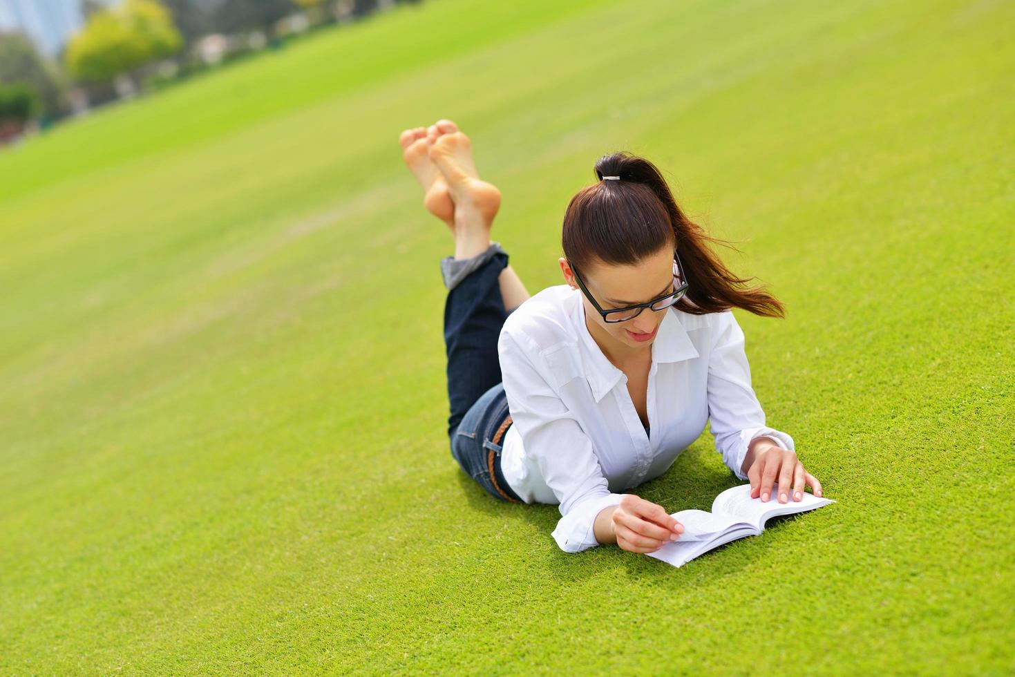 jonge vrouw die een boek in het park leest foto