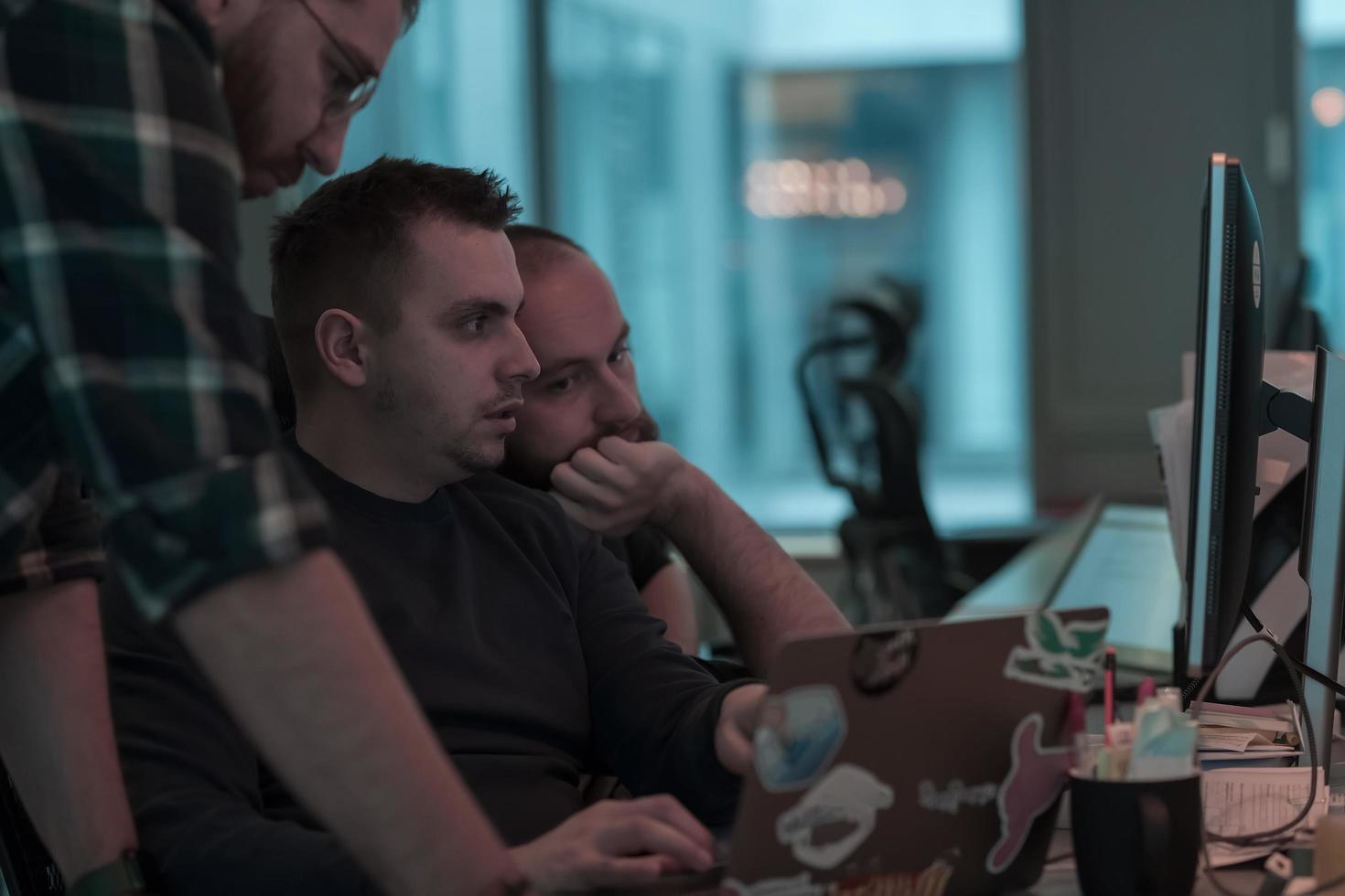 een foto van drie mannen staren aandachtig Bij een computer terwijl zittend in een modern kantoor. selectief focus