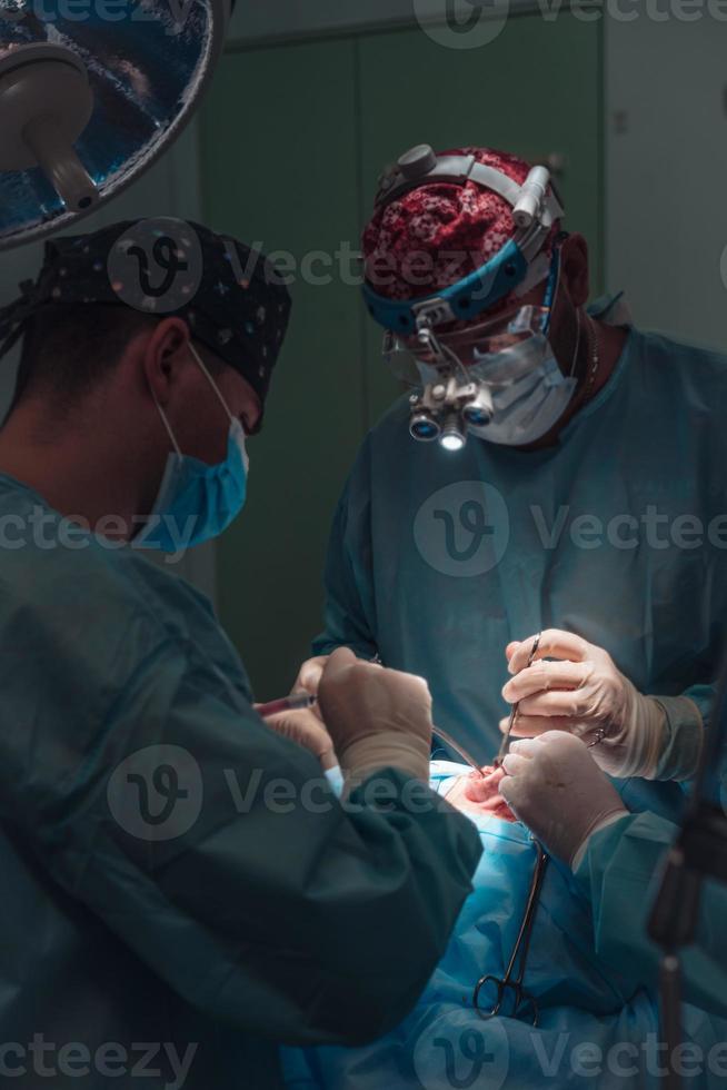 chirurg en zijn assistent het uitvoeren van kunstmatig chirurgie Aan neus- foto