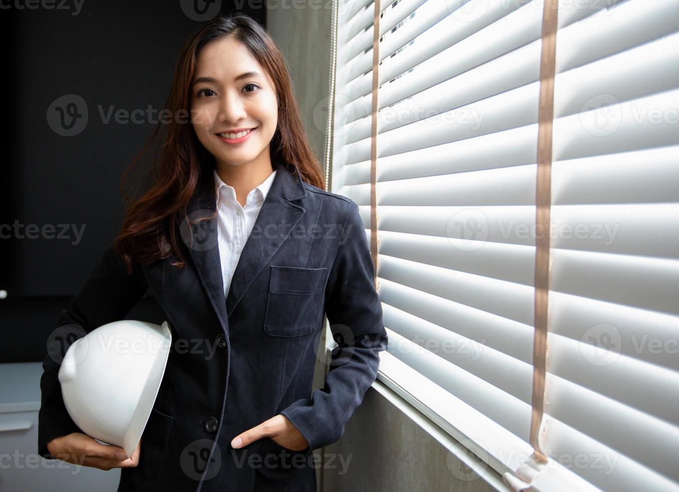 professioneel Aziatisch vrouw ingenieur staand vol vertrouwen glimlachen in de kantoor foto