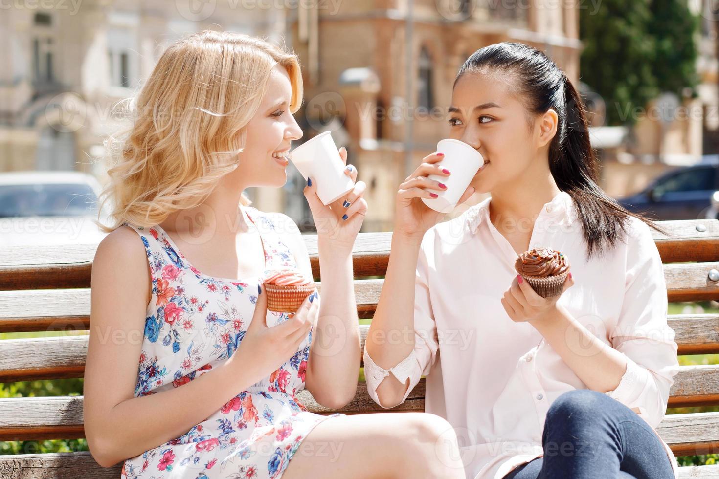 twee vriendinnen in park met koffie en cakejes foto