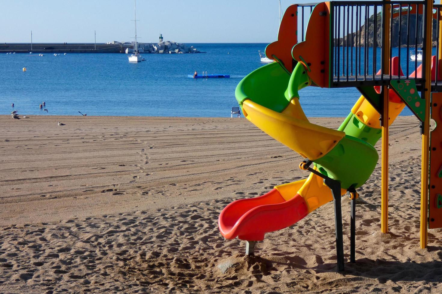 kleurrijk glijbaan Aan de zand van de strand, kinderen spellen foto