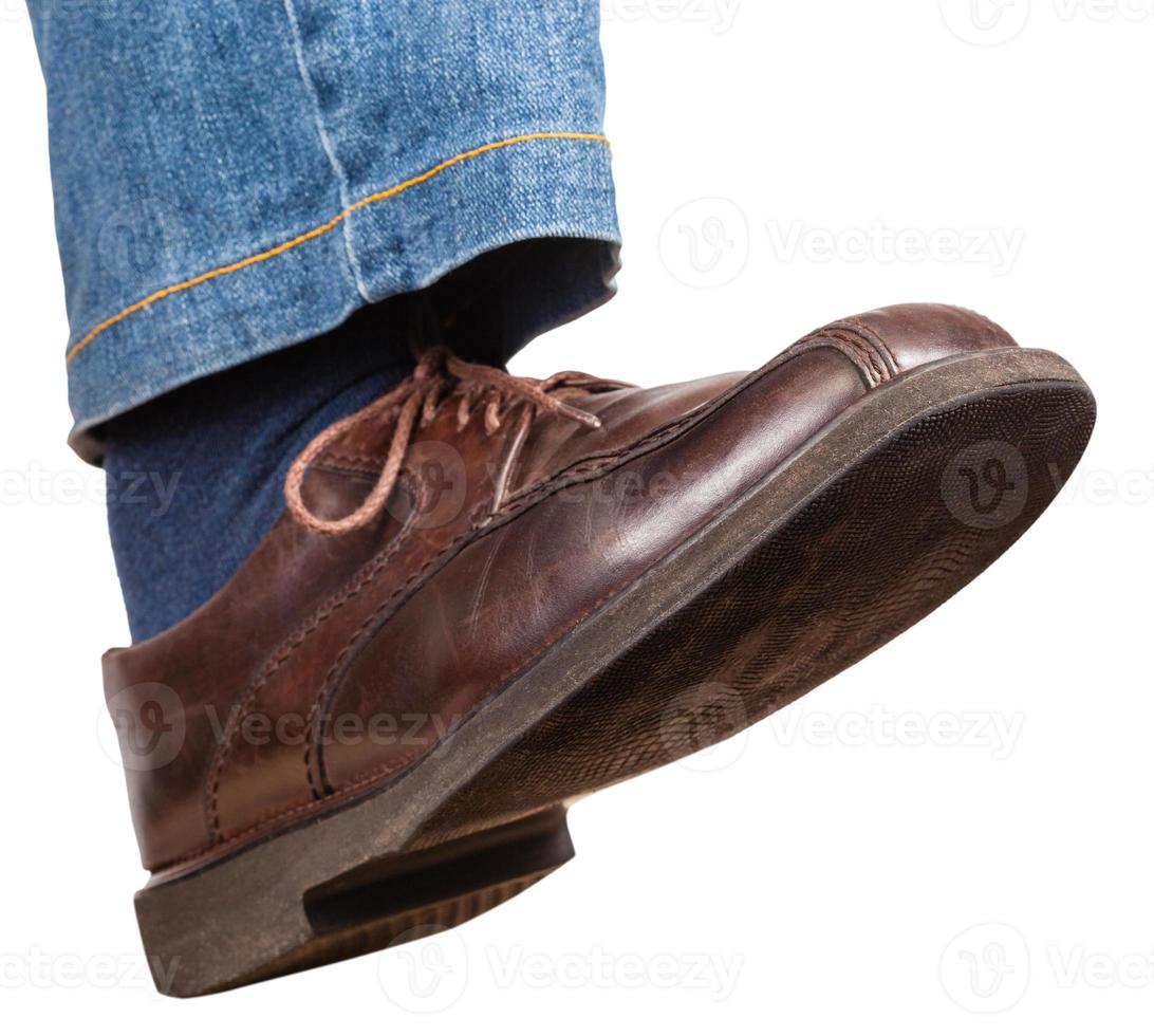 stap van mannetje Rechtsaf been in jeans en bruin schoen foto